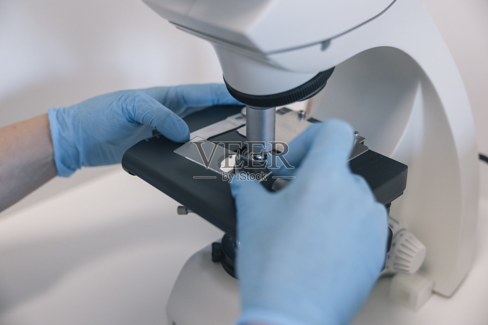 医生在实验室中调整显微镜载玻片进行医学研究照片摄影图片