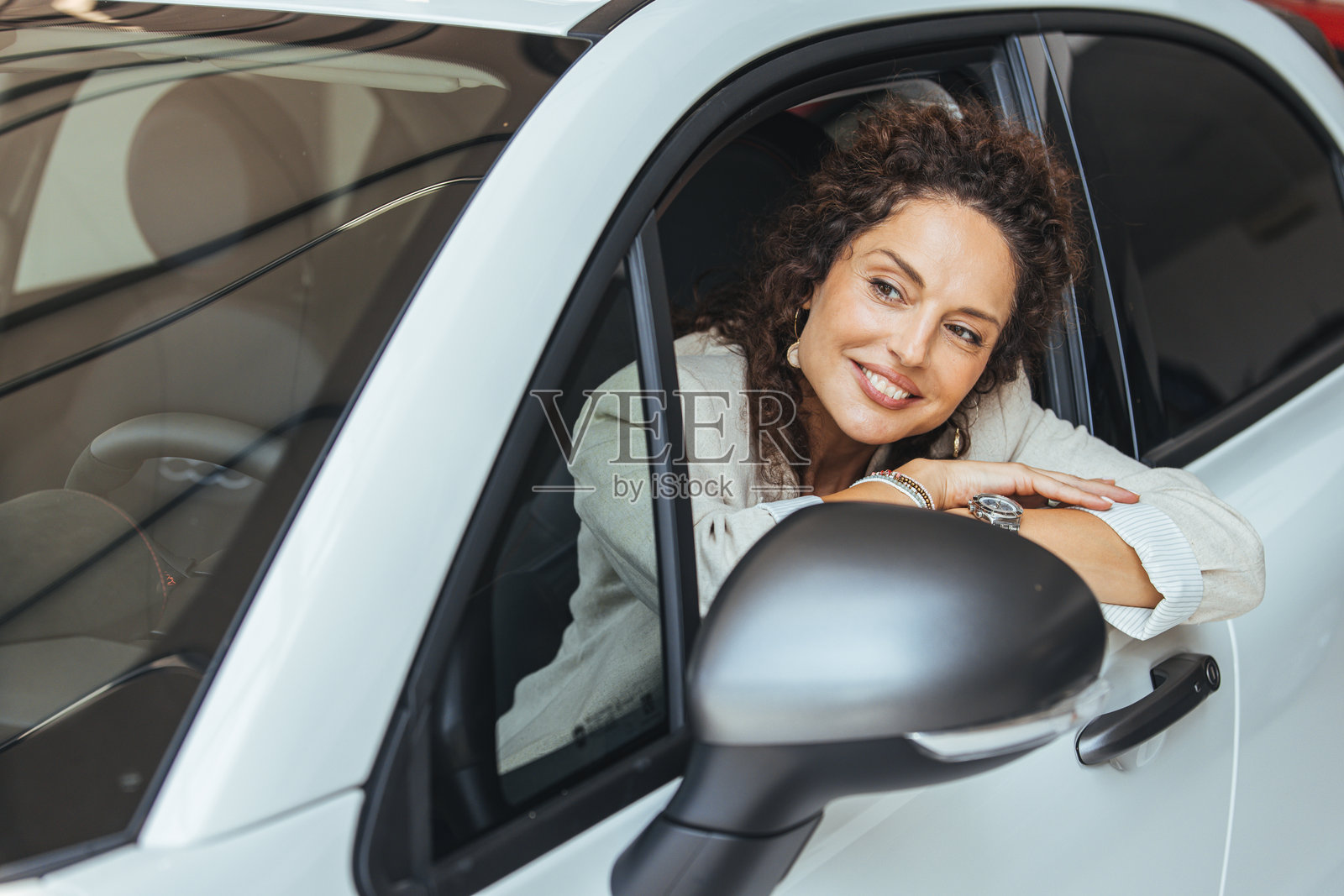 微笑的女性在城市环境中透过白色汽车窗户向外看照片摄影图片