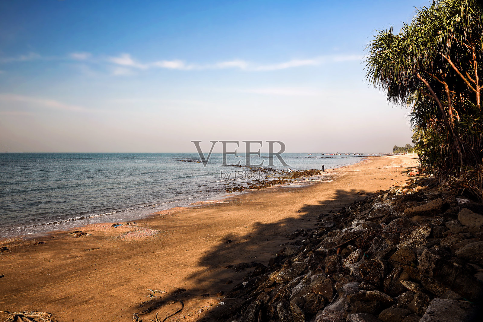 宁静的黄昏日落时热带海滩与岩石海岸线照片摄影图片