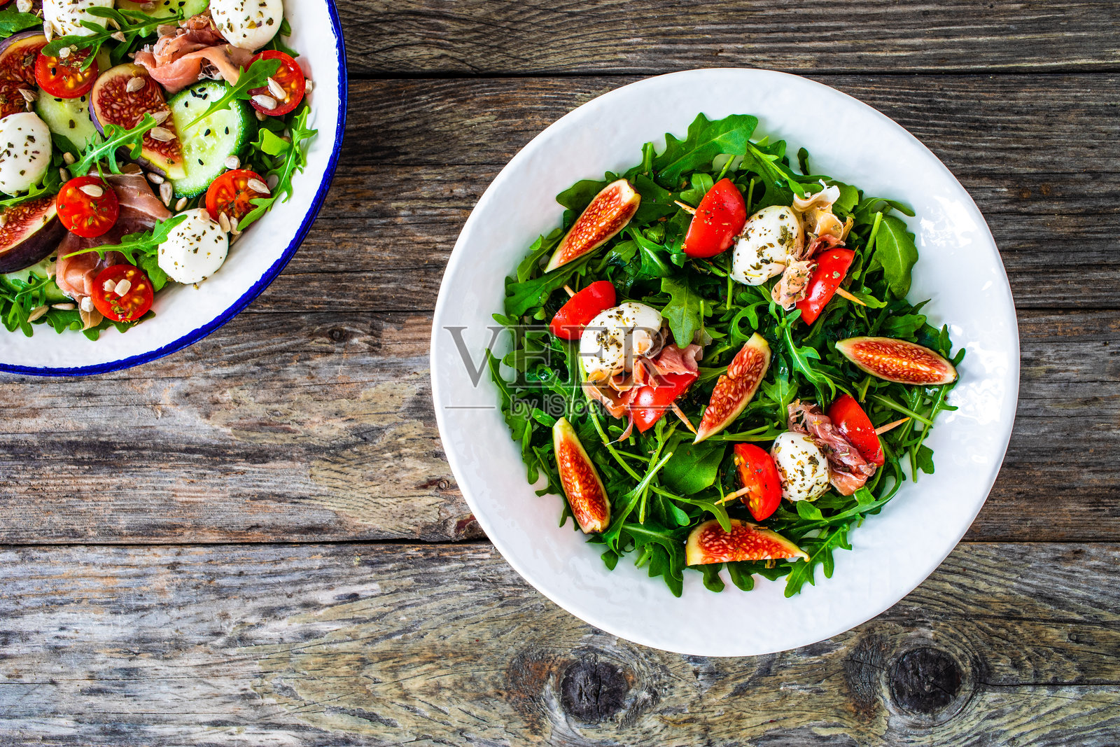 美味沙拉 - 马苏里拉奶酪、无花果、樱桃番茄和新鲜绿叶蔬菜放在木桌上照片摄影图片