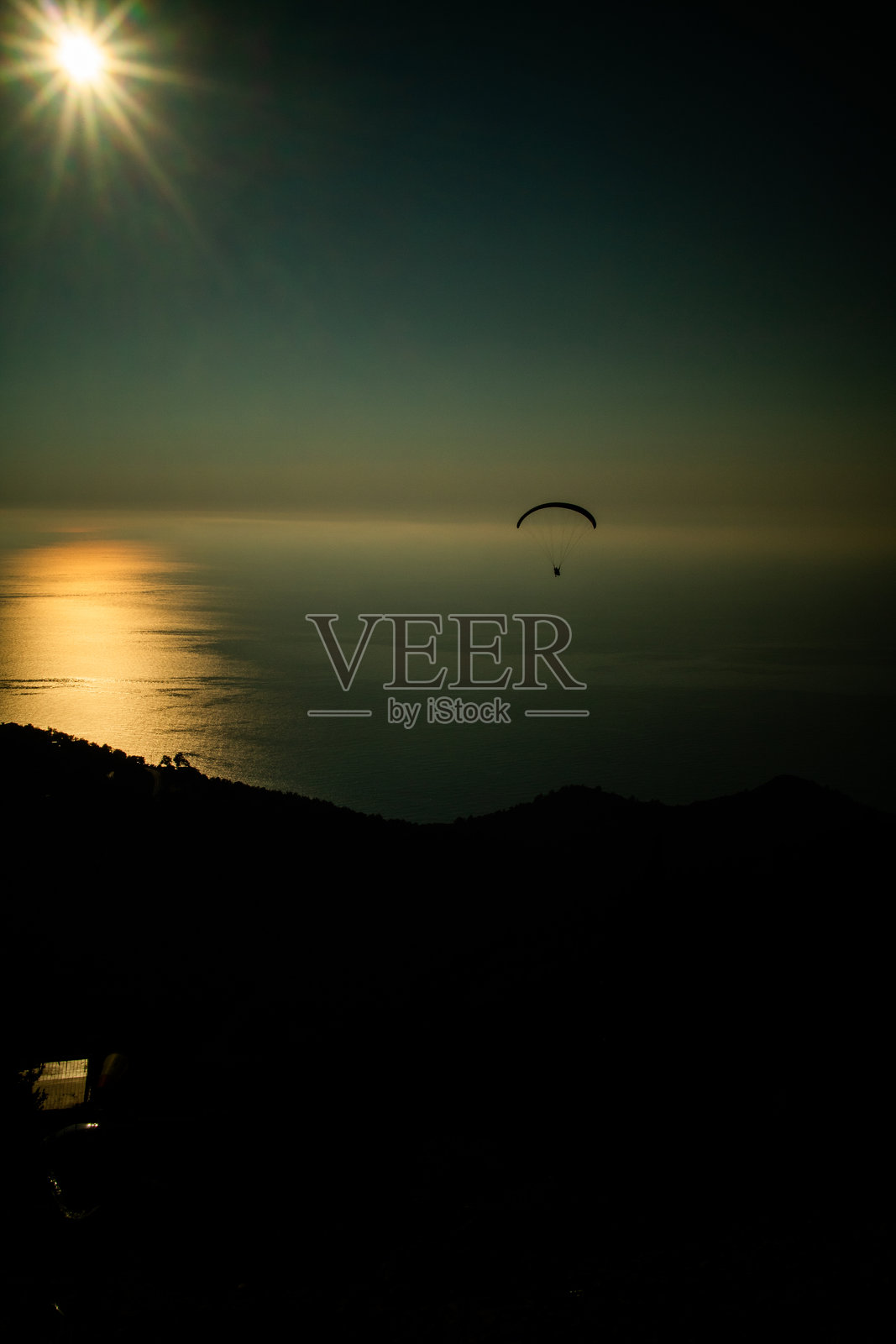 在宁静的海洋水面上，日落时分的滑翔伞飞行，展现出宁静的自然风光照片摄影图片