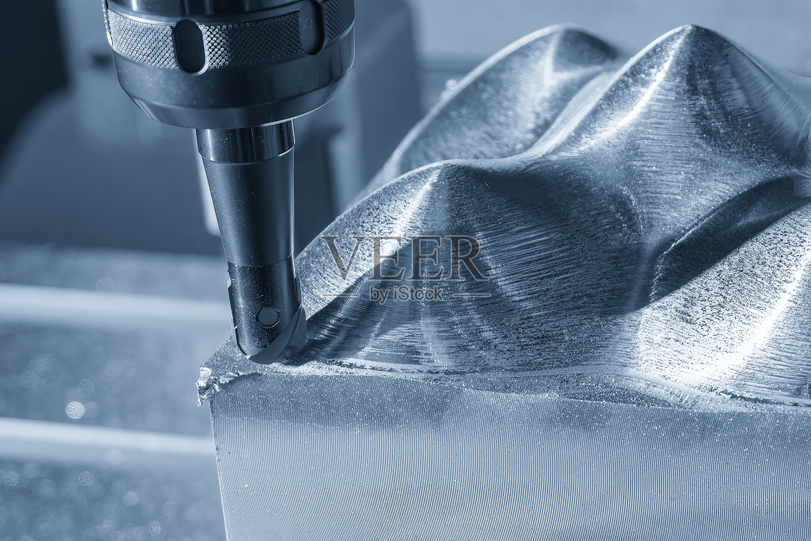 数控铣床使用可换刀具在蓝色调中粗加工模具零件。照片摄影图片