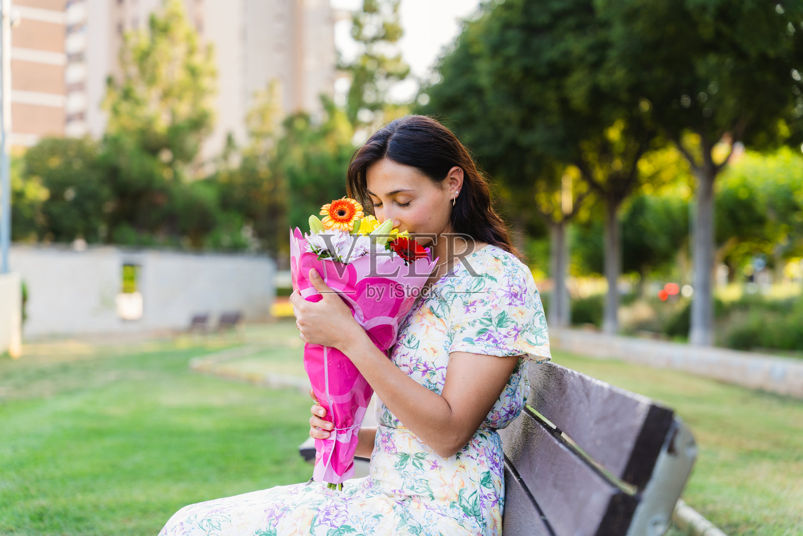 年轻女性在公园里闻花束照片摄影图片