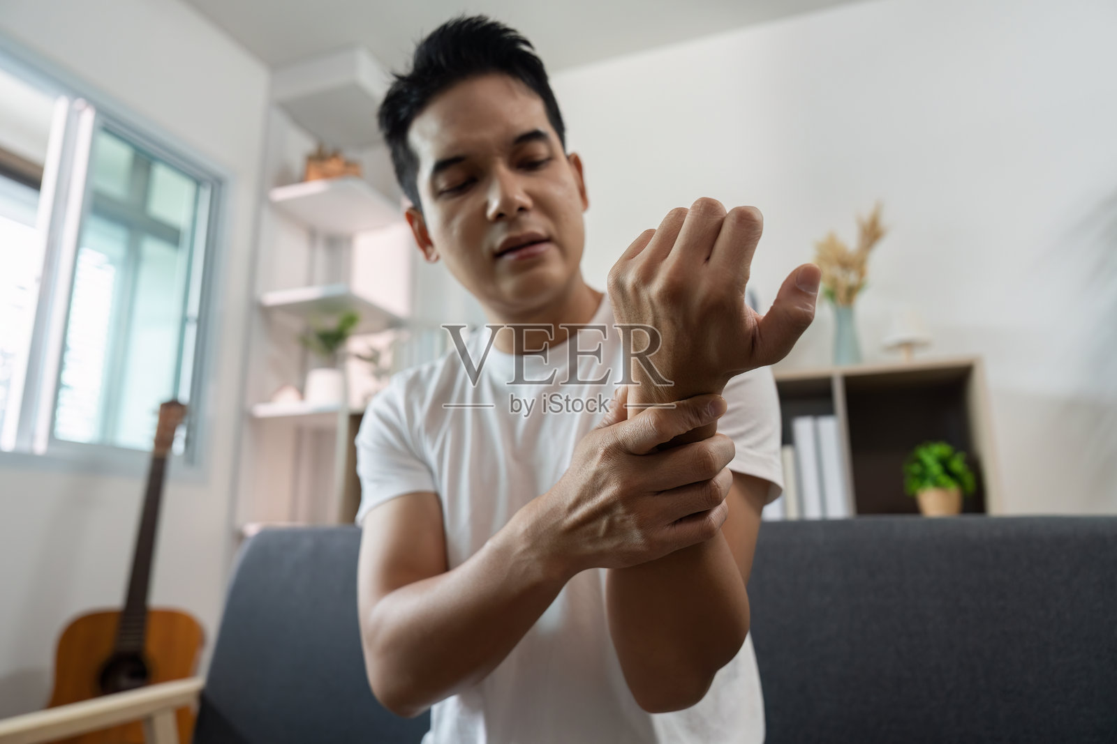 健康。年轻男子在家中处理手腕疼痛和不适。照片摄影图片