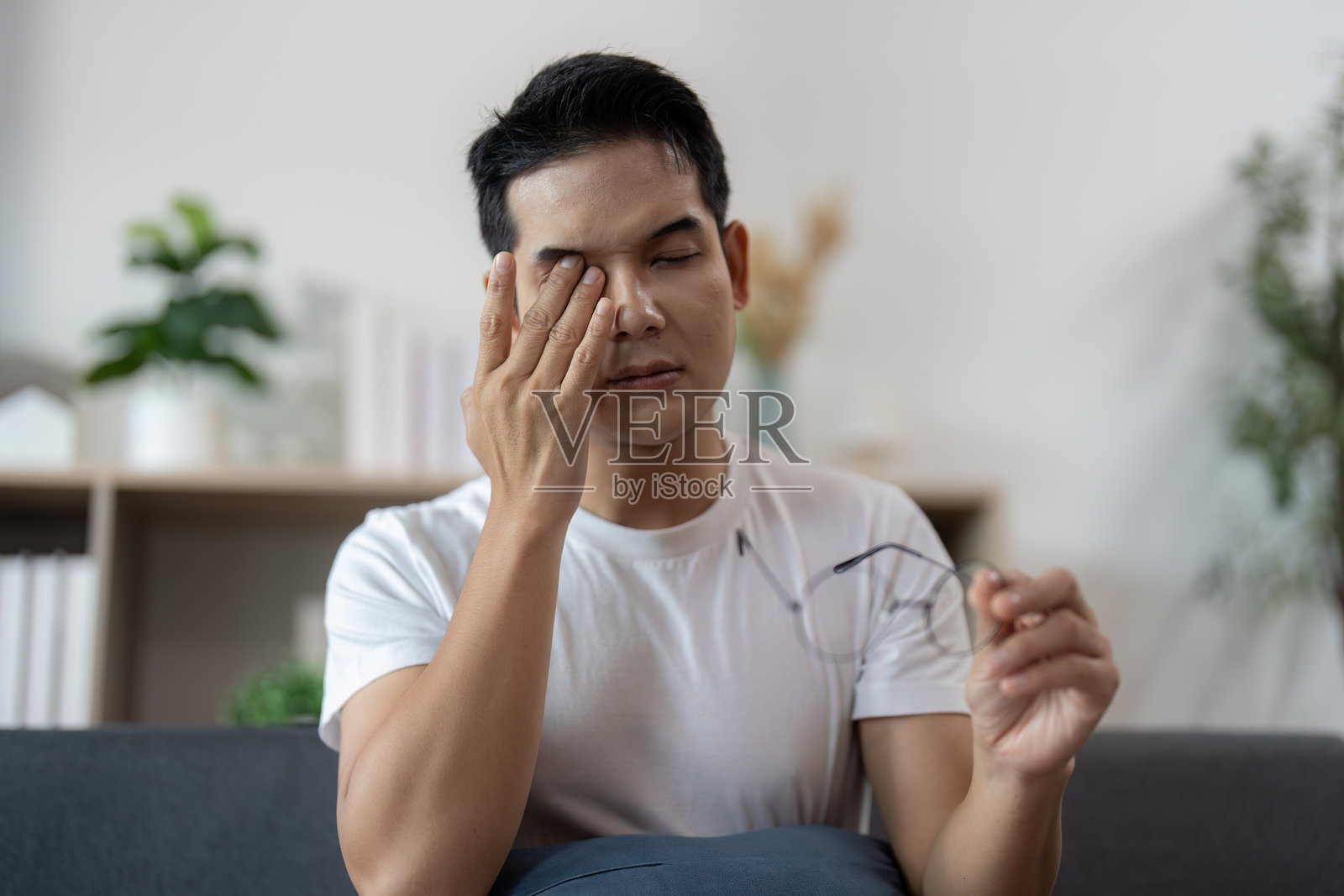 压力缓解。年轻男子因眼睛疲劳而拿着眼镜。照片摄影图片