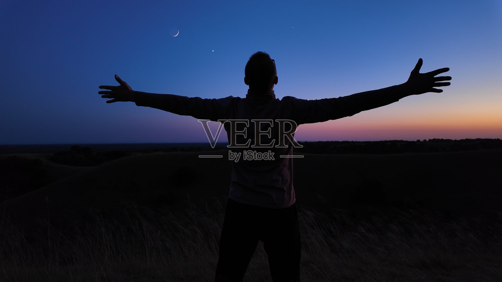 月光下，星星和行星映衬下的乡村与男人的剪影，蓝色时光。照片摄影图片