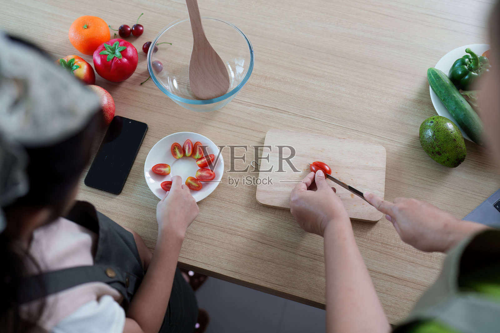 烹饪乐趣：母女一起切番茄照片摄影图片