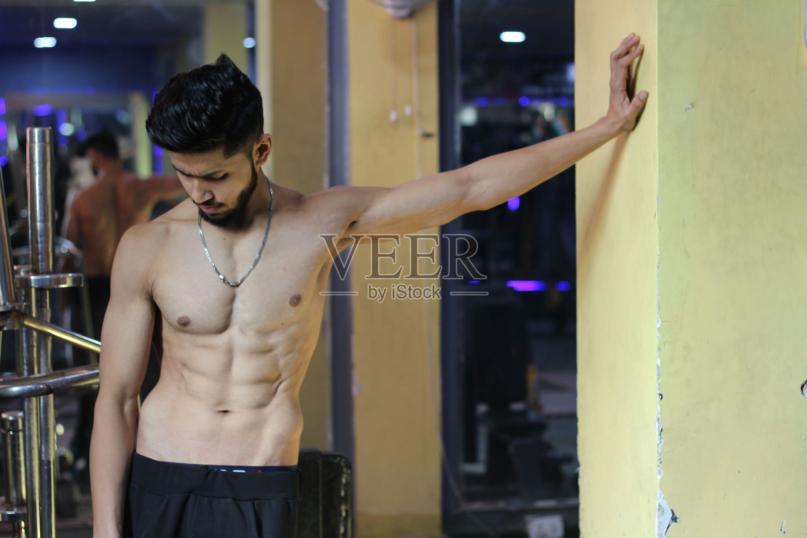 肌肉发达的印度男子站在黄色墙壁前照片摄影图片