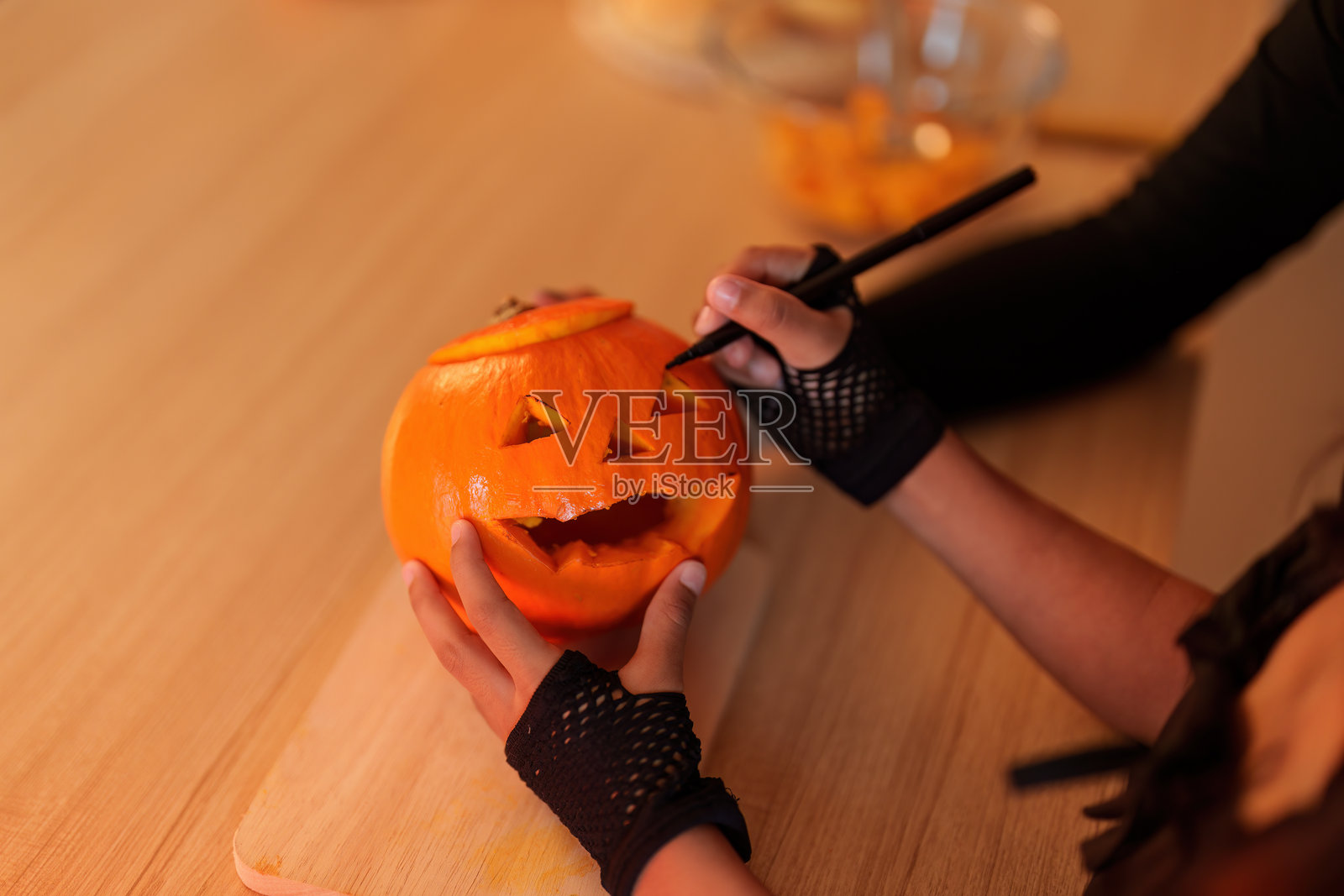 万圣节南瓜雕刻。孩子在成人监督下制作恐怖的杰克南瓜灯。照片摄影图片