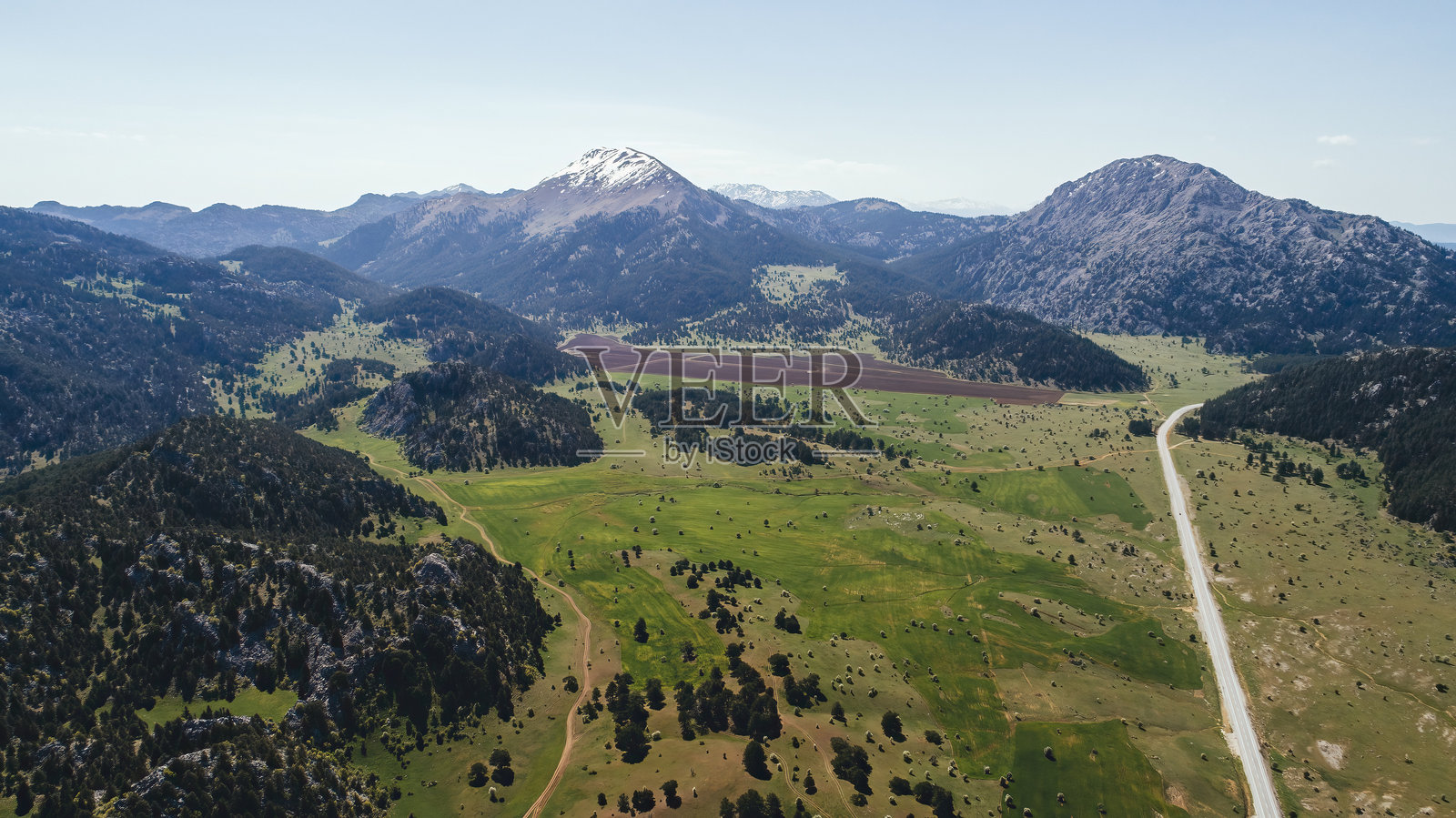 绿植间的机动车道。背景中雄伟的群山映照在相机上。照片摄影图片