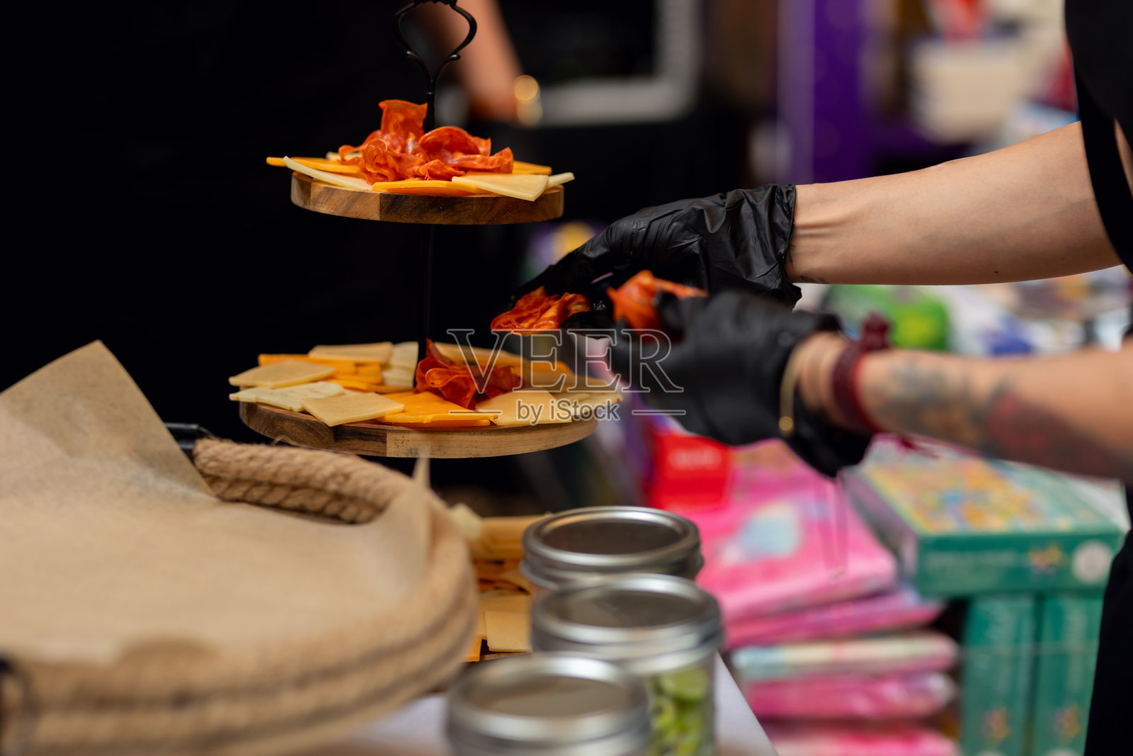 穿着黑手套的餐饮服务人员在宴会中摆放奶酪和腌制肉类的冷盘拼盘照片摄影图片