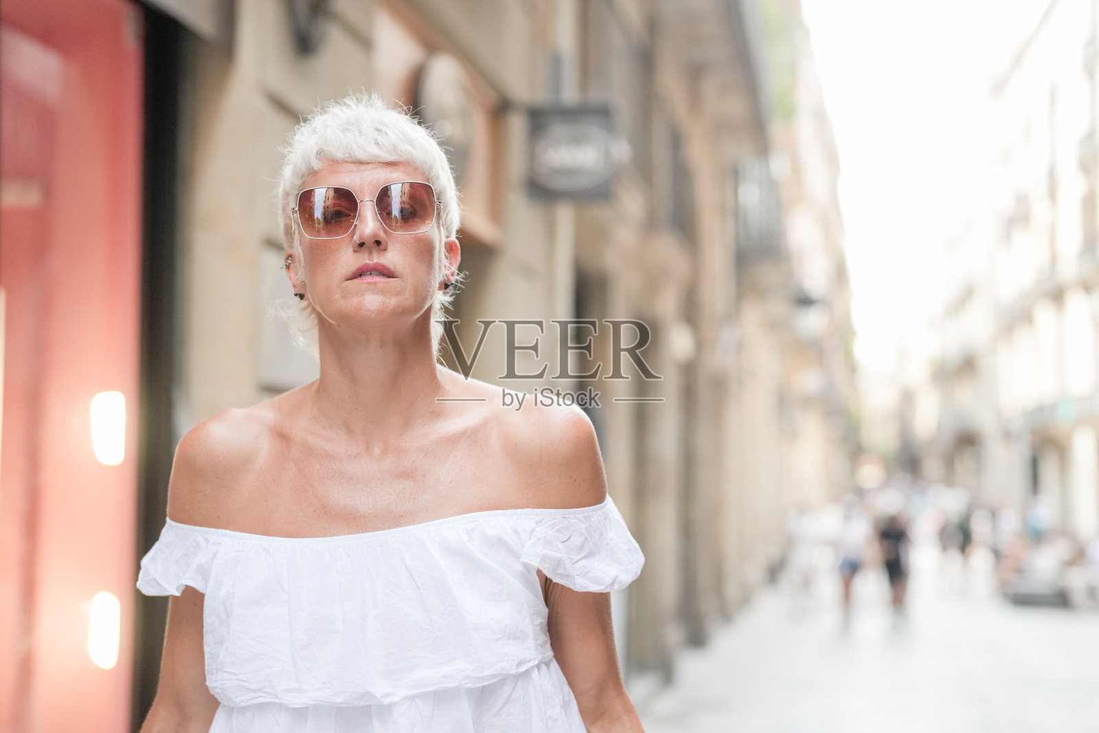 一位穿着白色连衣裙的女性正与其他几个人一起走在街上。照片摄影图片