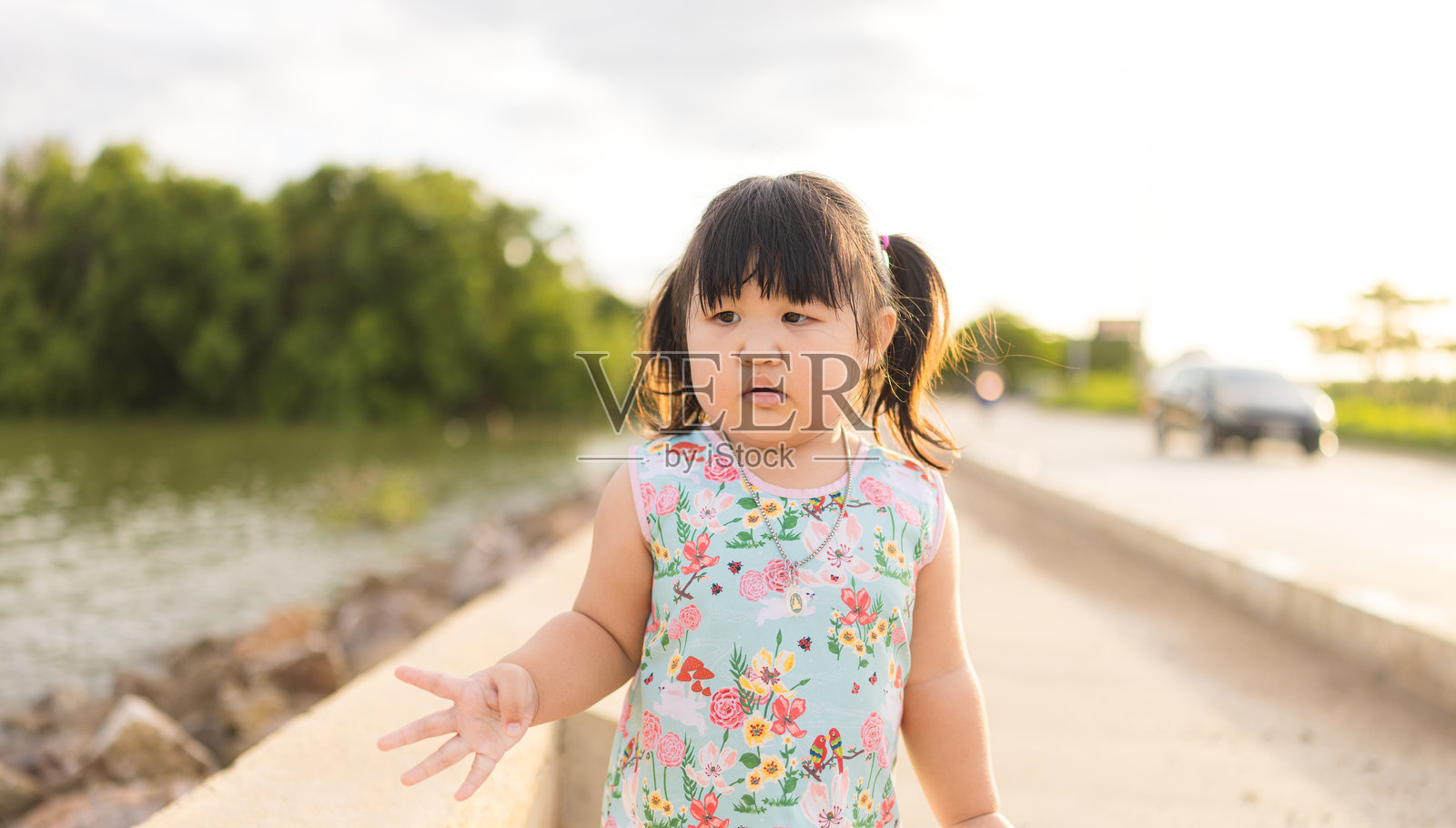 一个可爱的小女孩在傍晚的公园里快乐地跑来跑去，亚洲小女孩戴着帽子在果园里散步。照片摄影图片