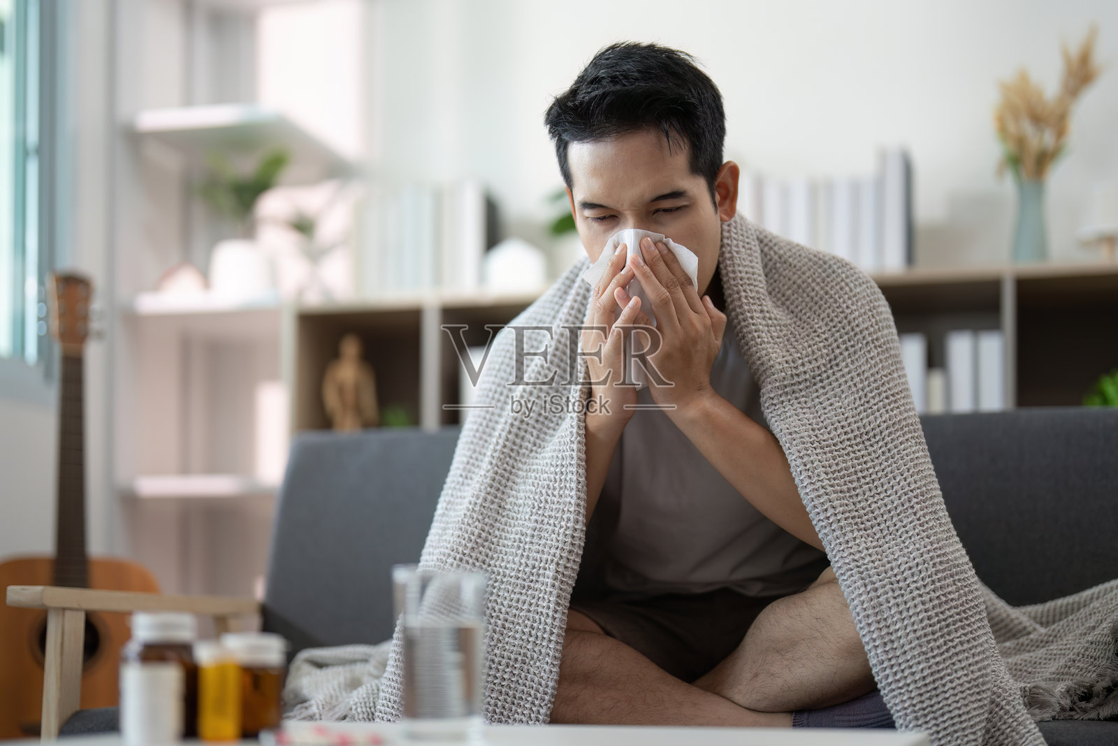 健康与保健。年轻男子在毯子下感到不适。照片摄影图片