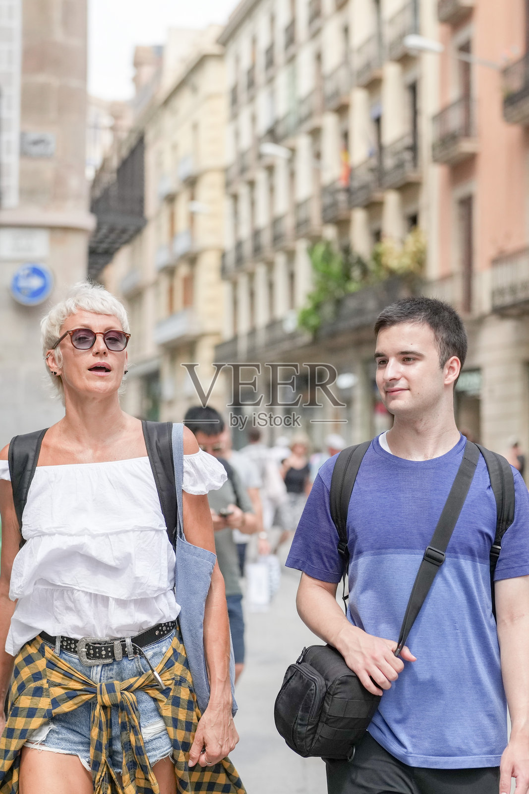 一男一女正在街上走，男士穿着蓝色衬衫。照片摄影图片