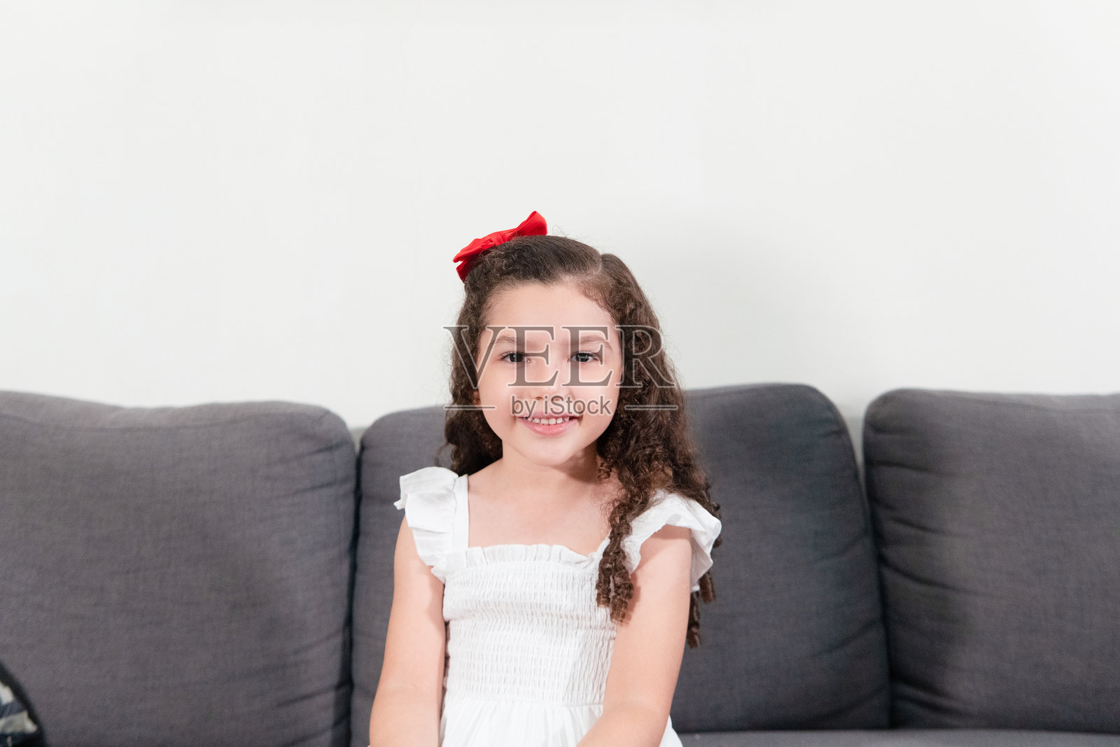 微笑的小女孩在家里的沙发上放松照片摄影图片