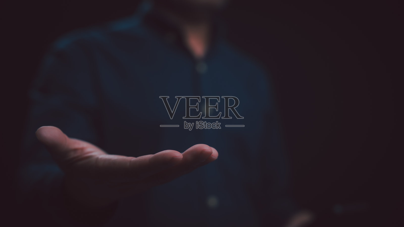 男人的手掌从黑暗中伸出，空荡荡的手心提供帮助。这个概念性的手势象征着支持、希望、慈善、给予、接受、需求、连接、人类的善良、同情、祈祷和信仰。照片摄影图片