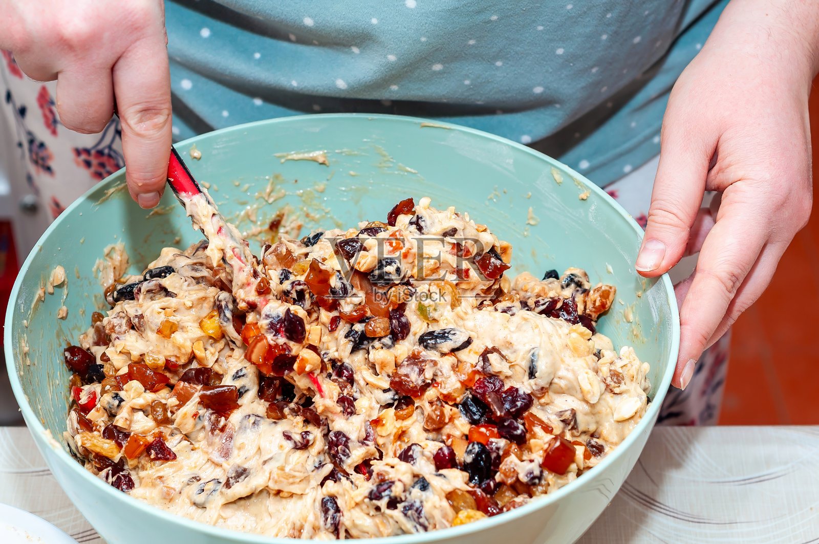 有人用刮刀搅拌水果蛋糕面糊，准备烘焙一种含有干果和坚果的节日美食。照片摄影图片