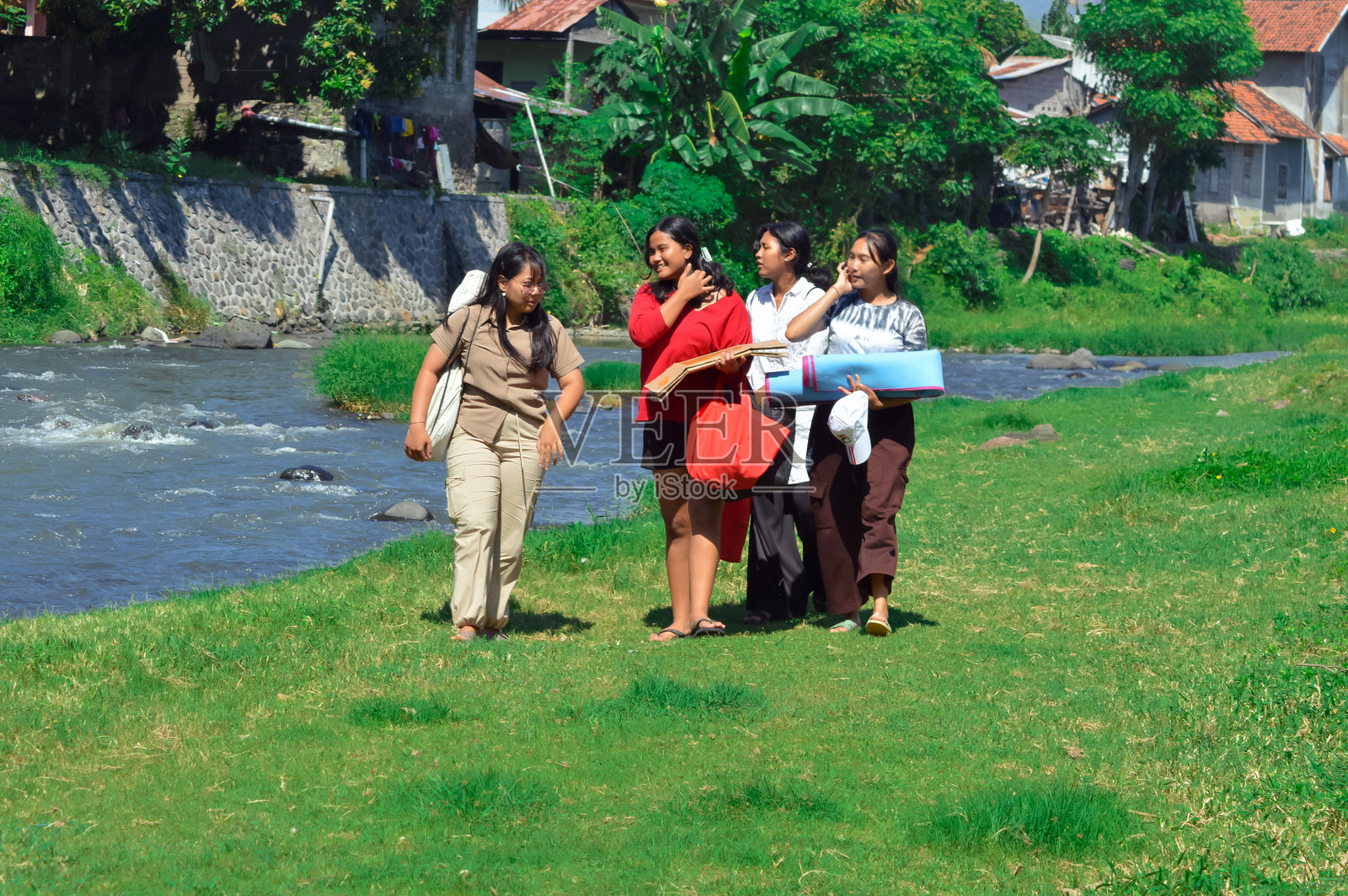 四个少女在河边小道上一起走回家照片摄影图片