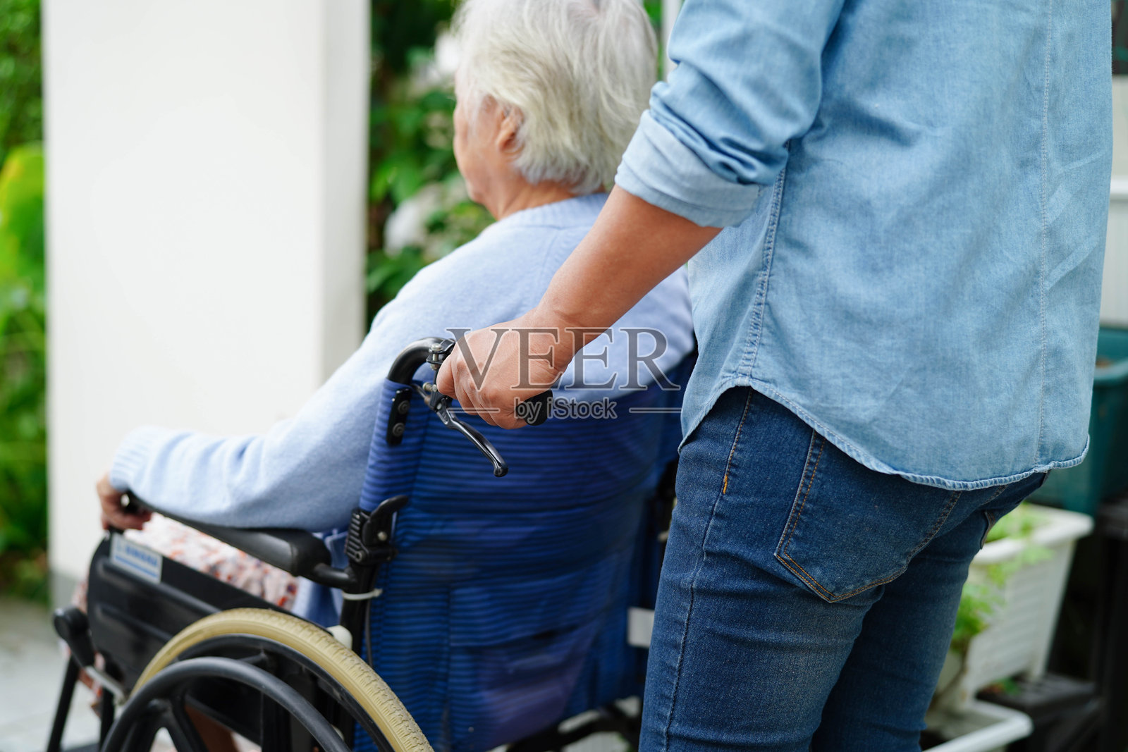 护理人员在医院帮助坐在轮椅上的亚洲老年残疾患者。照片摄影图片