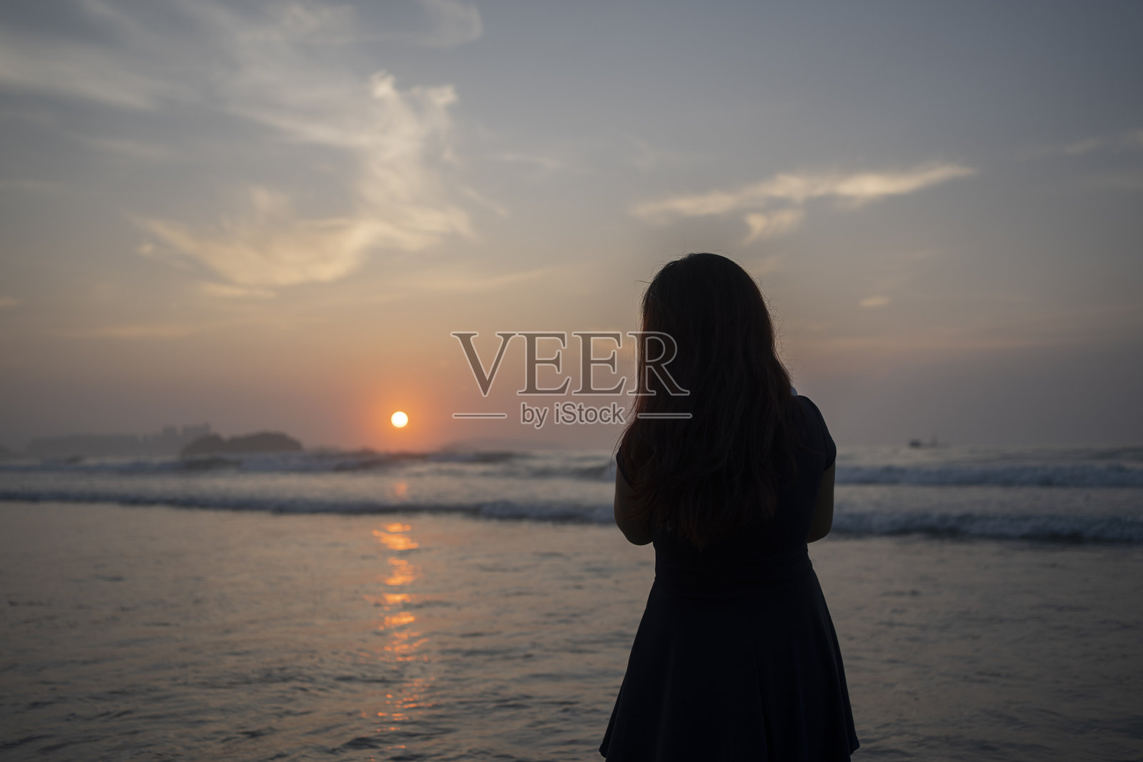 海边日出时，一位女性的剪影抱着她的婴儿照片摄影图片