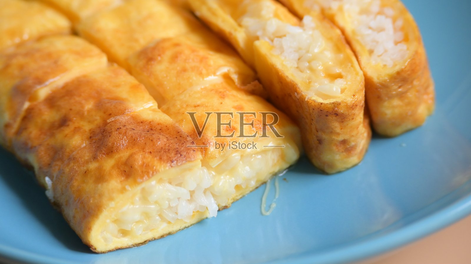 蓝色盘子上的奶酪和米饭卷蛋饼，美味的早餐。照片摄影图片