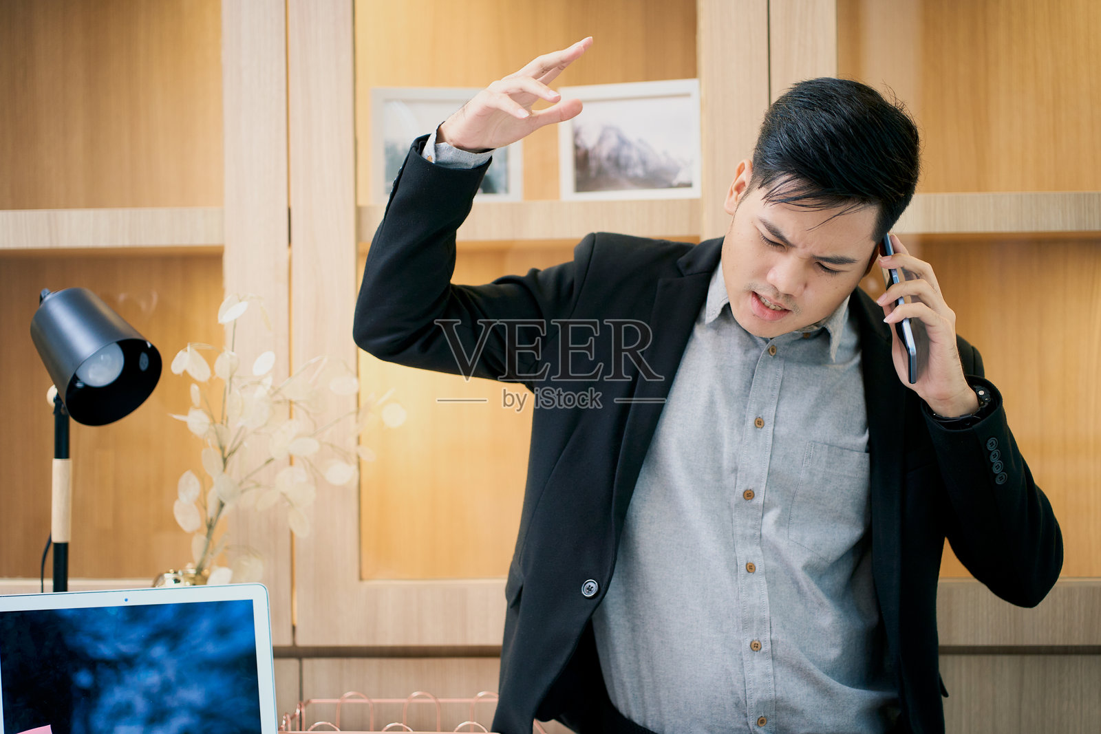 亚洲商人在办公室里因打电话而生气照片摄影图片