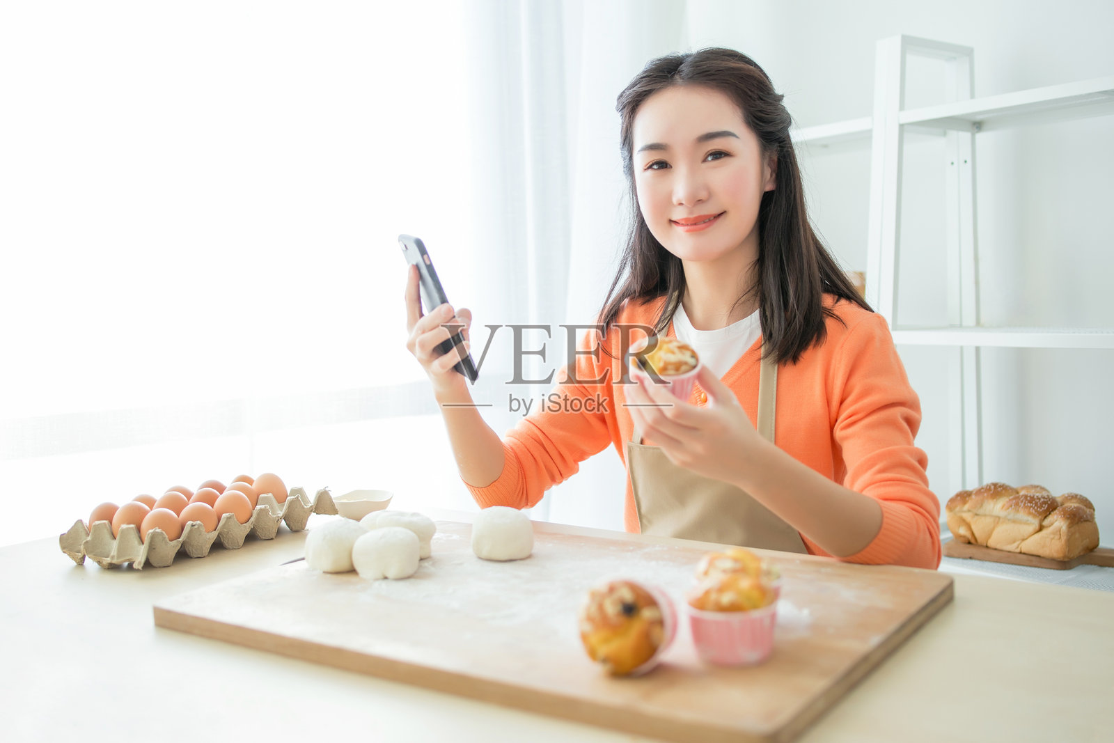 年轻女性用智能手机拍摄自制糕点照片摄影图片