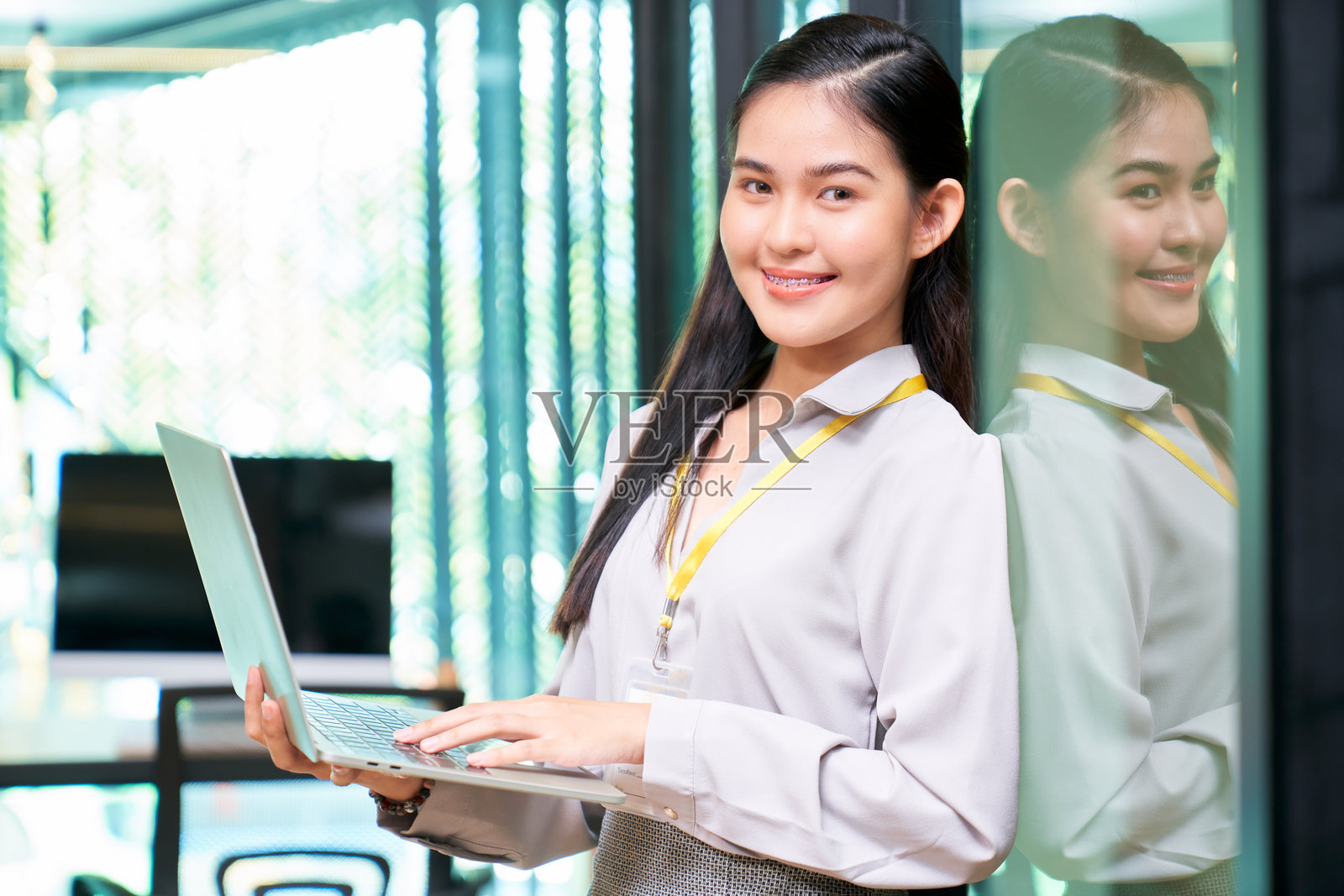 在办公室里工作的年轻女商人肖像，手中拿着笔记本电脑。照片摄影图片