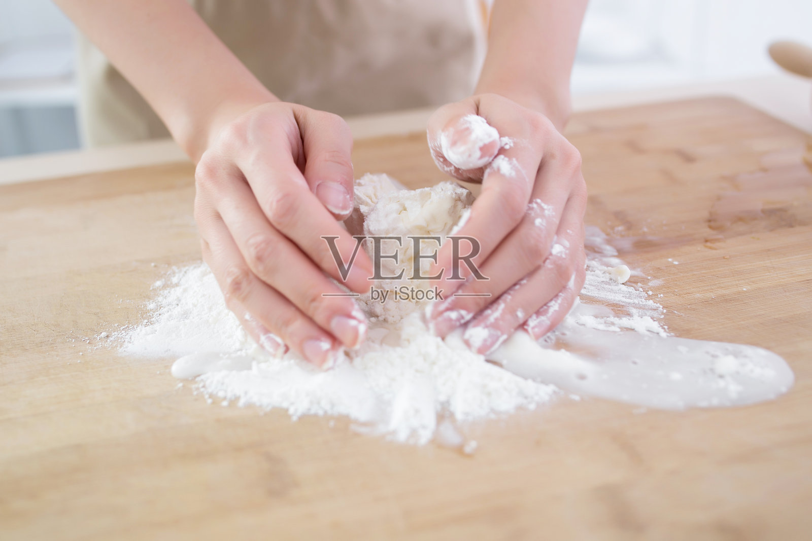 双手在木质表面上揉面粉，准备烘焙。照片摄影图片