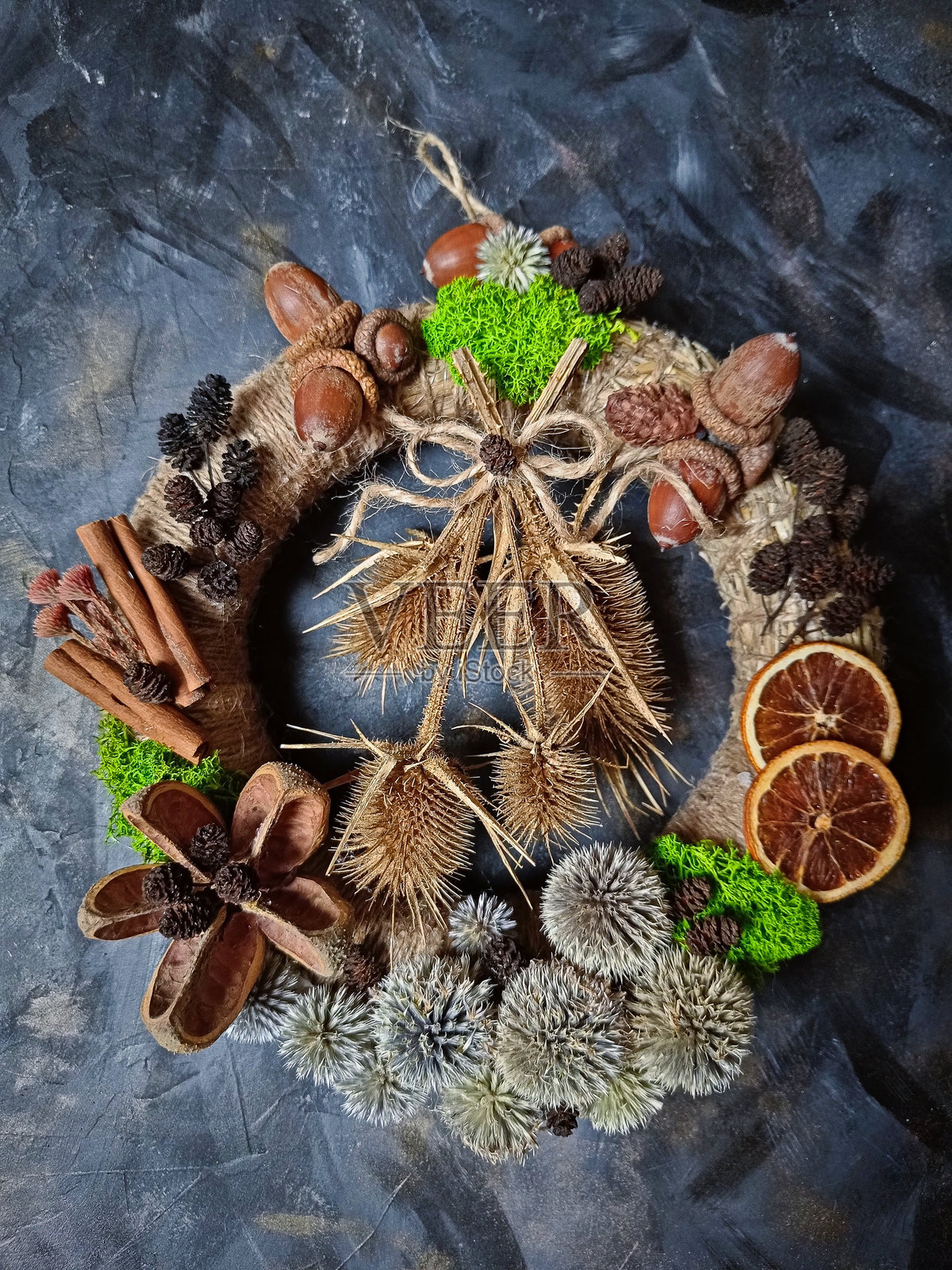 乡村风格的圣诞花环，装饰有干橙片、肉桂棒、橡果和天然种子，底座为黄麻材质。照片摄影图片