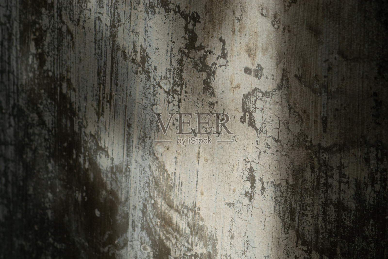 一个抽象的磨损纹理背景，展示了一面风化、剥落的混凝土墙，伴随着戏剧性的对角光影。照片摄影图片