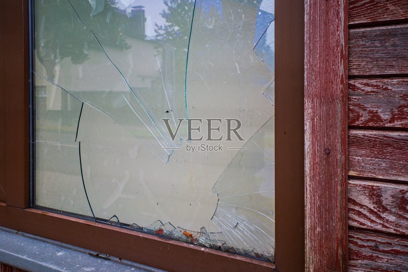 木框架中破碎的窗户特写，玻璃碎片散落一地。照片摄影图片