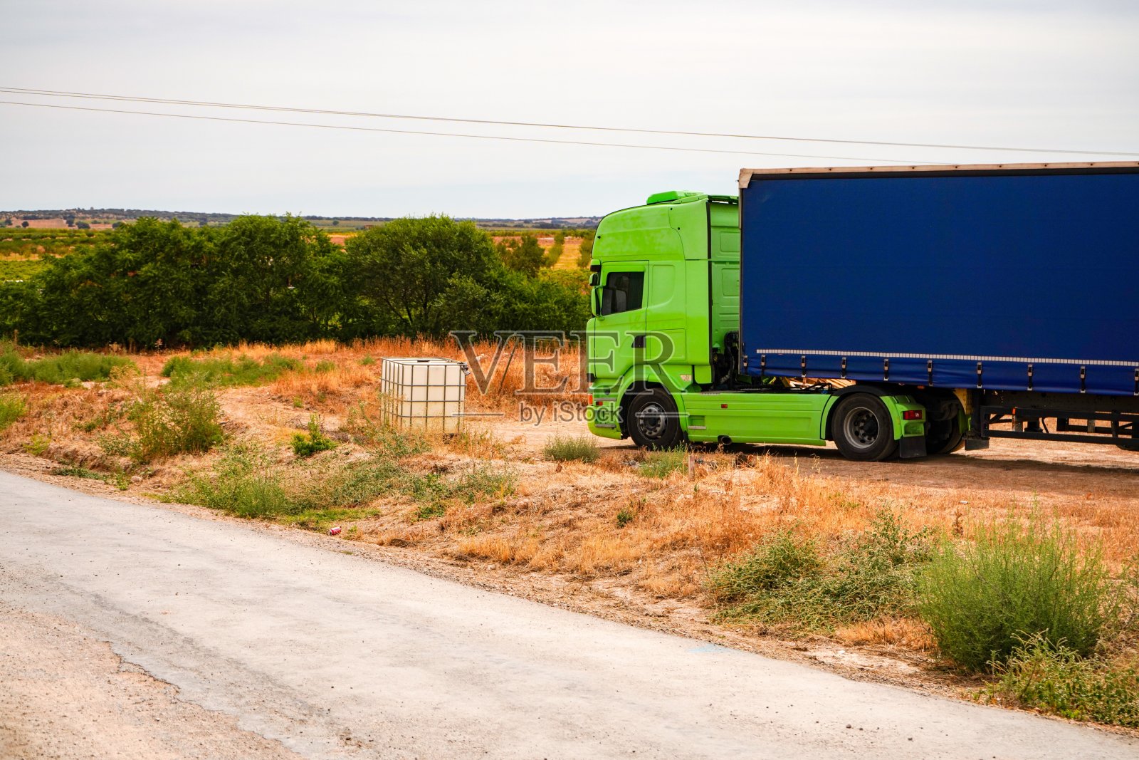 一辆绿色驾驶室和蓝色拖车的卡车。照片摄影图片
