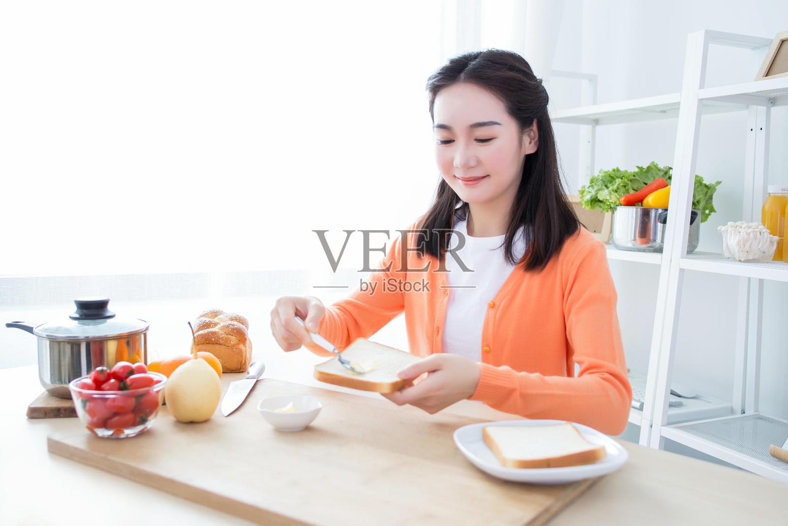 年轻女性在桌子上准备早餐，桌上摆满了各种食物照片摄影图片