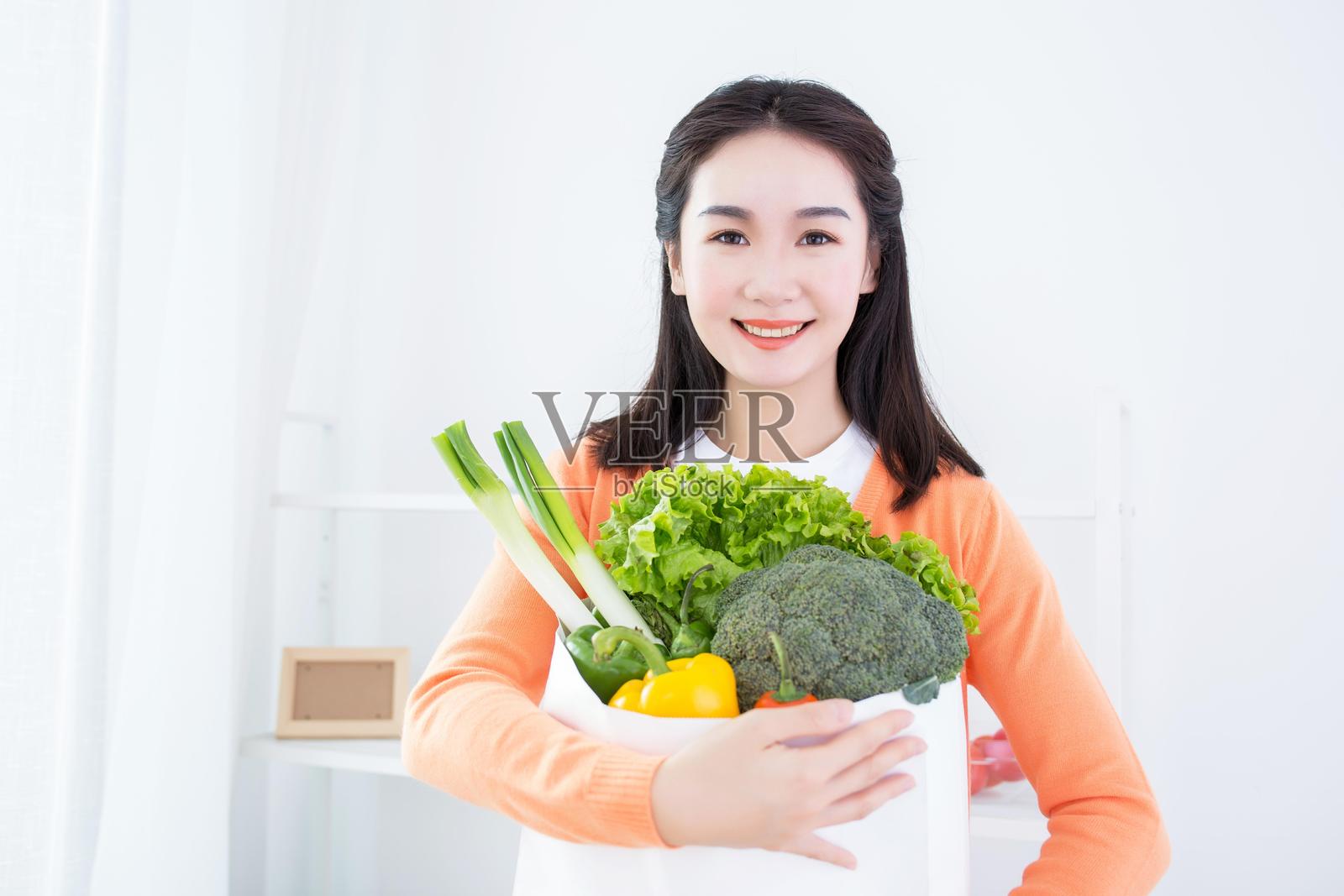 一位女性在明亮的房间里手持新鲜蔬菜照片摄影图片