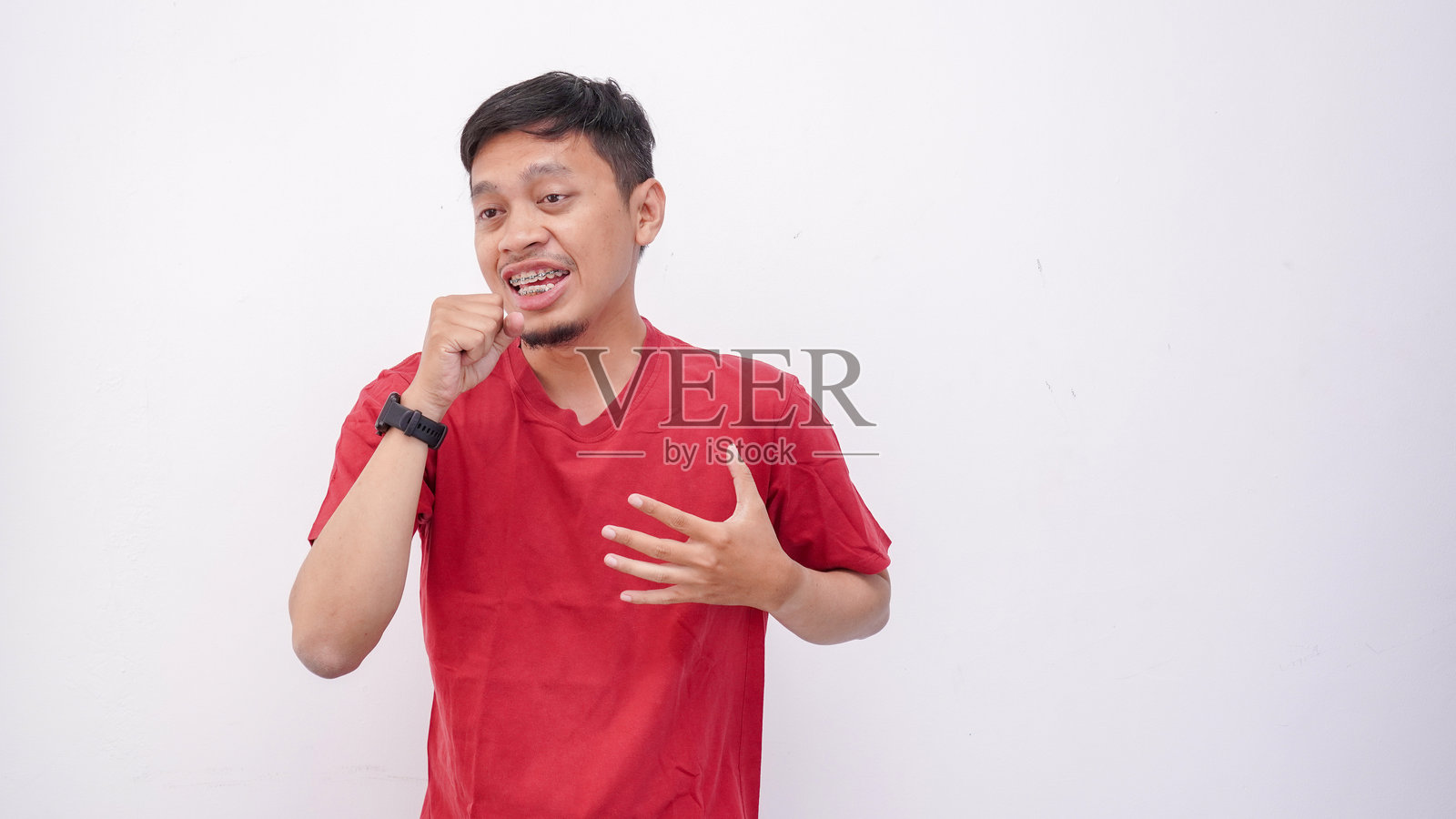 亚洲男子假装用想象中的麦克风唱歌，伴随着充满活力的手势，享受音乐表演的时刻。年轻的亚洲男孩在白色背景下展现乐趣、热情和情感。照片摄影图片