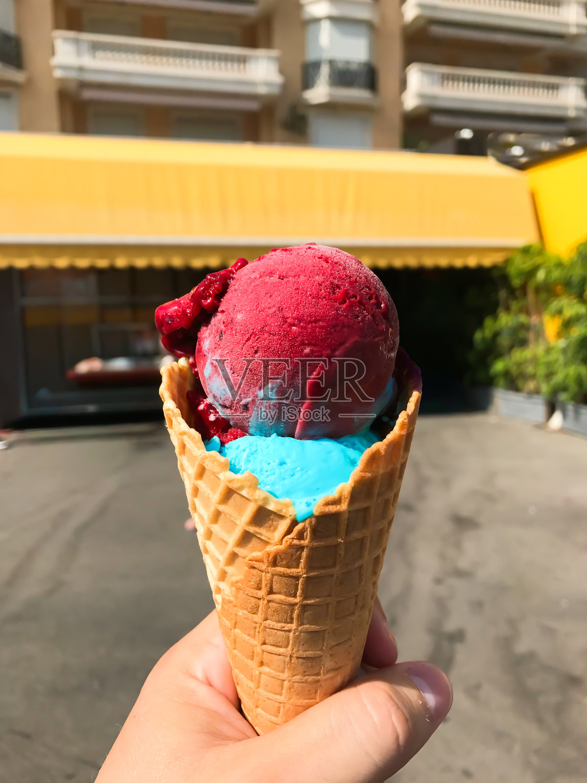 一个人手持一个粉蓝漩涡的冰淇淋蛋筒照片摄影图片