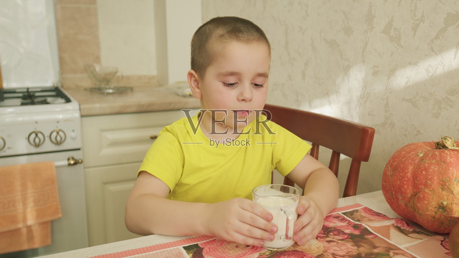 一个年轻的孩子在温馨的厨房环境中快乐地喝着一杯清爽的牛奶照片摄影图片