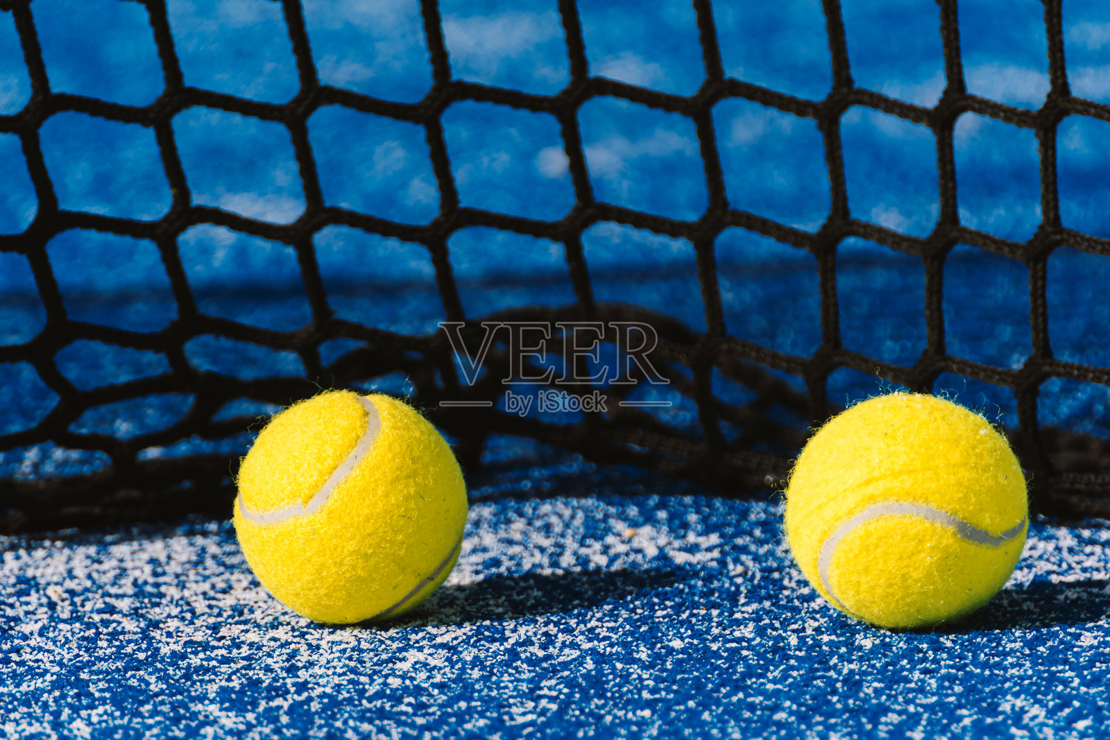 蓝色球场上的两个网球，背景是网子，完美的搭档照片摄影图片