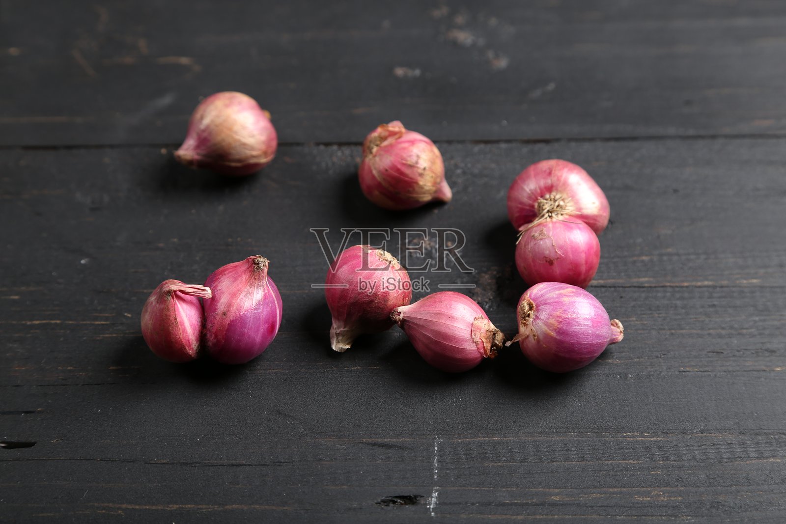 新鲜的带皮小葱和去皮小葱放在深色木质表面上照片摄影图片