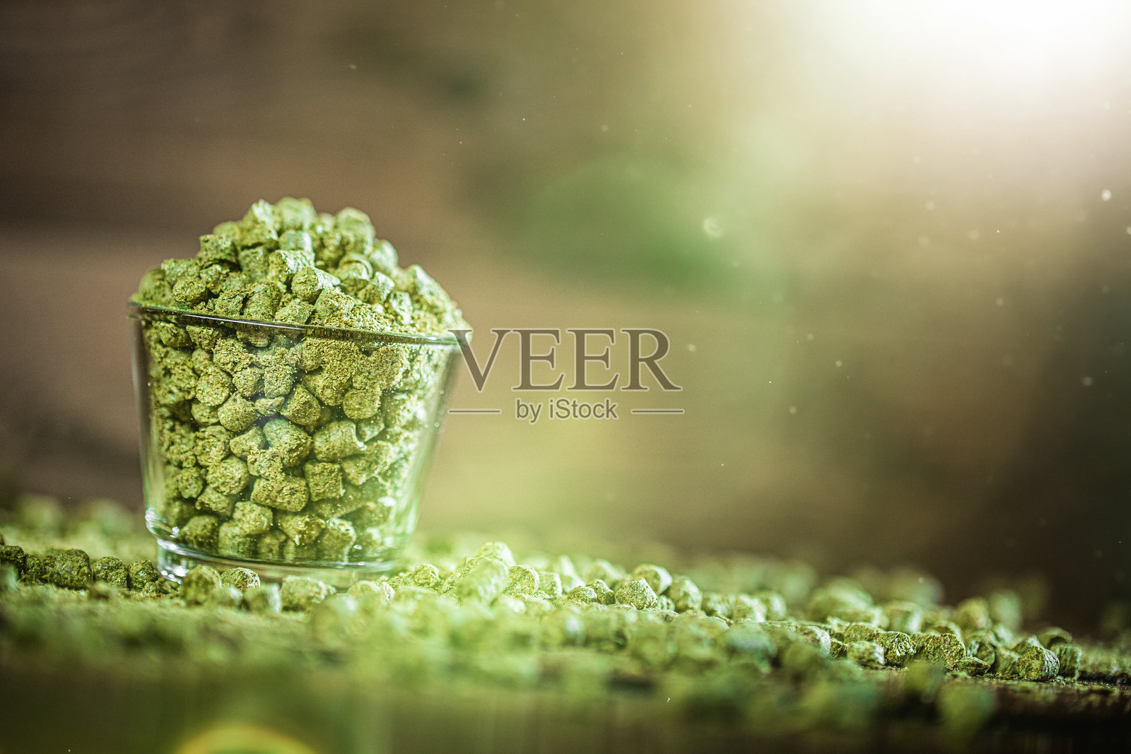 绿色糖晶在一个玻璃容器中排列，闪烁的光线在其表面反射，背景为乡村风格。照片摄影图片