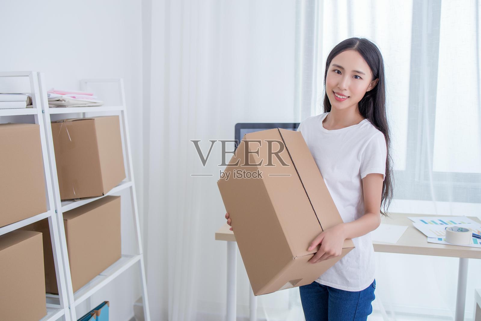 年轻女性在有书架的房间里拿着纸箱照片摄影图片