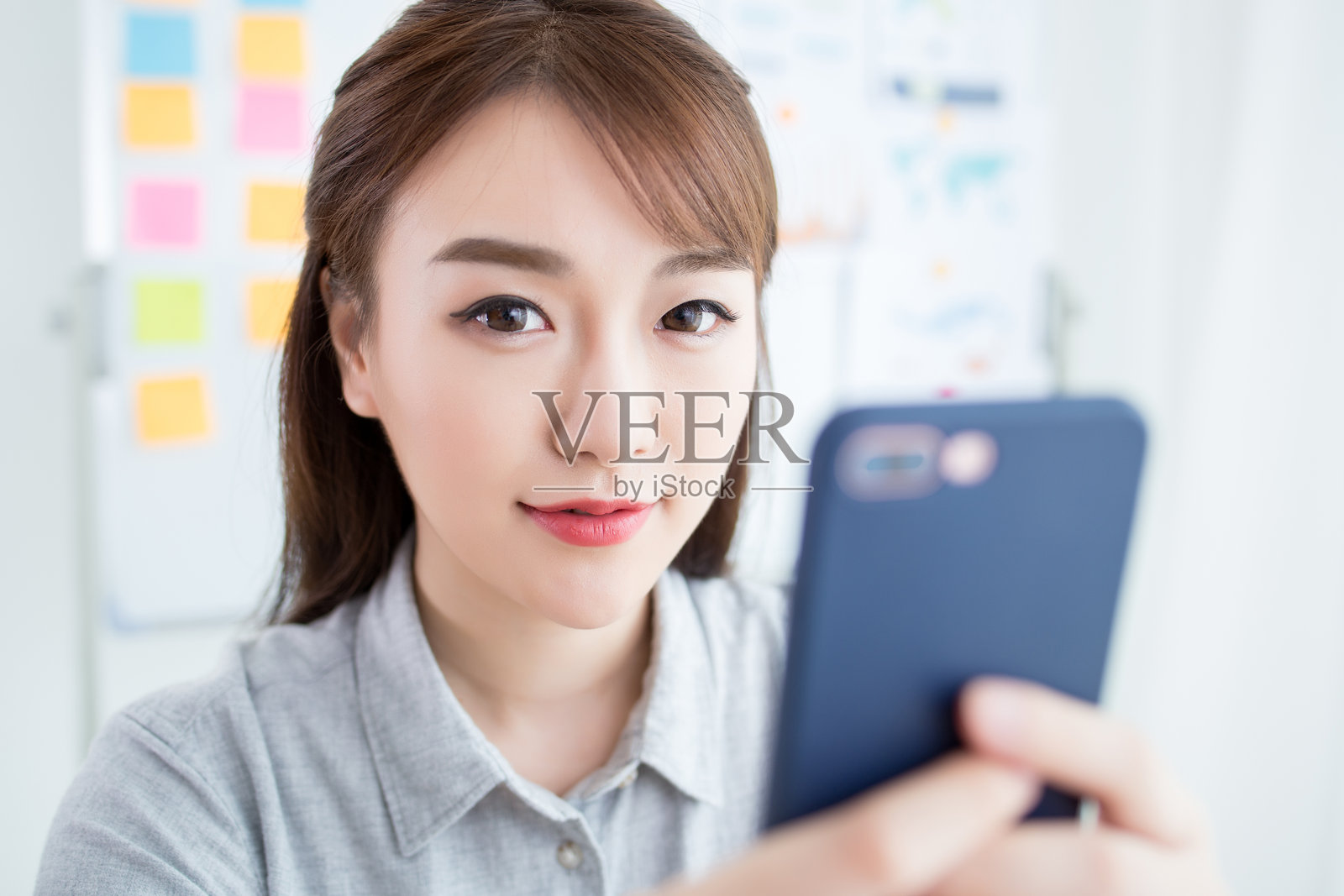 年轻女性在办公室环境中使用智能手机照片摄影图片