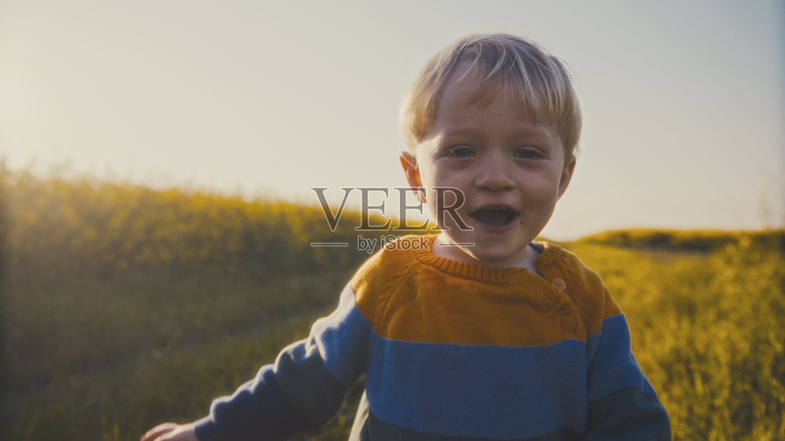 快乐的幼儿在日落时分的田野中玩耍照片摄影图片