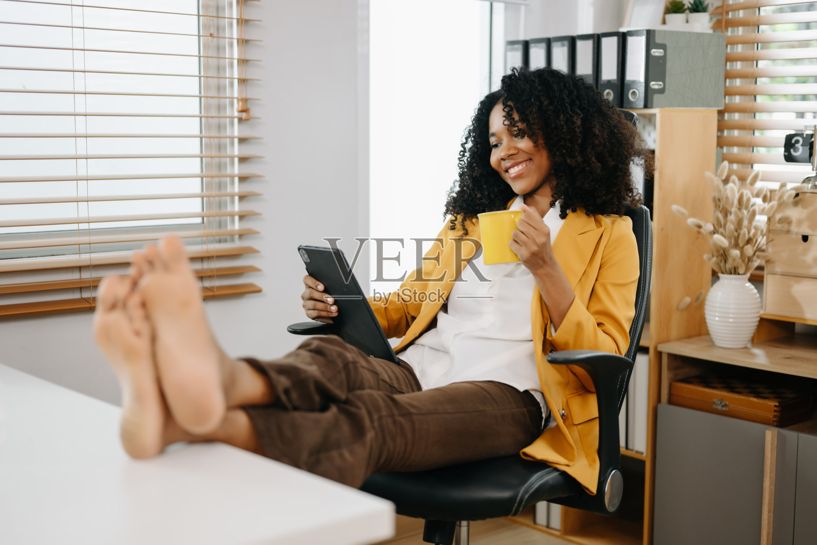 女商人在现代办公室享受咖啡休息，使用平板电脑，放松身心照片摄影图片