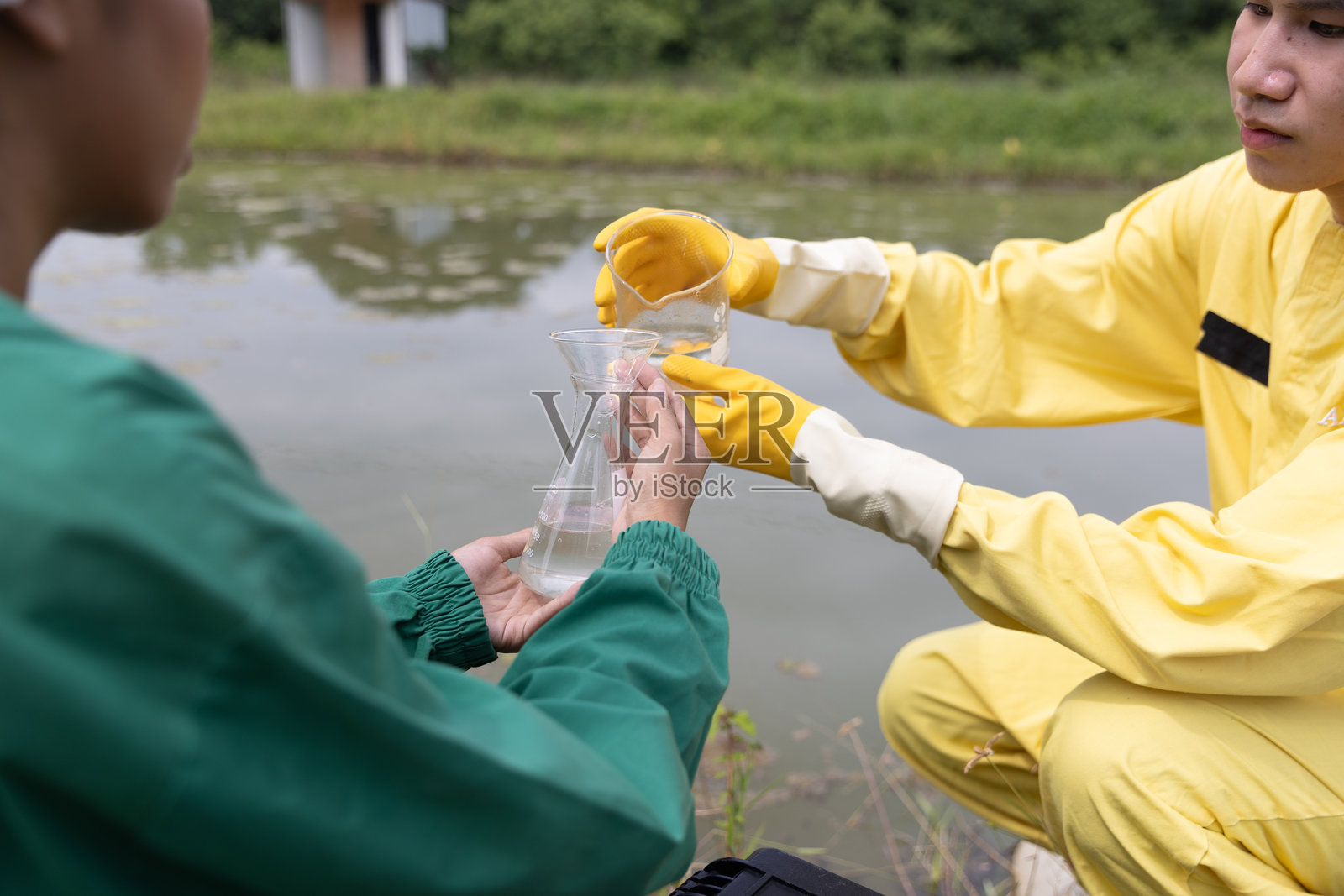 水质控制工作人员和科学家穿着个人防护装备，正在采样水并分析水质，工业与环境。照片摄影图片