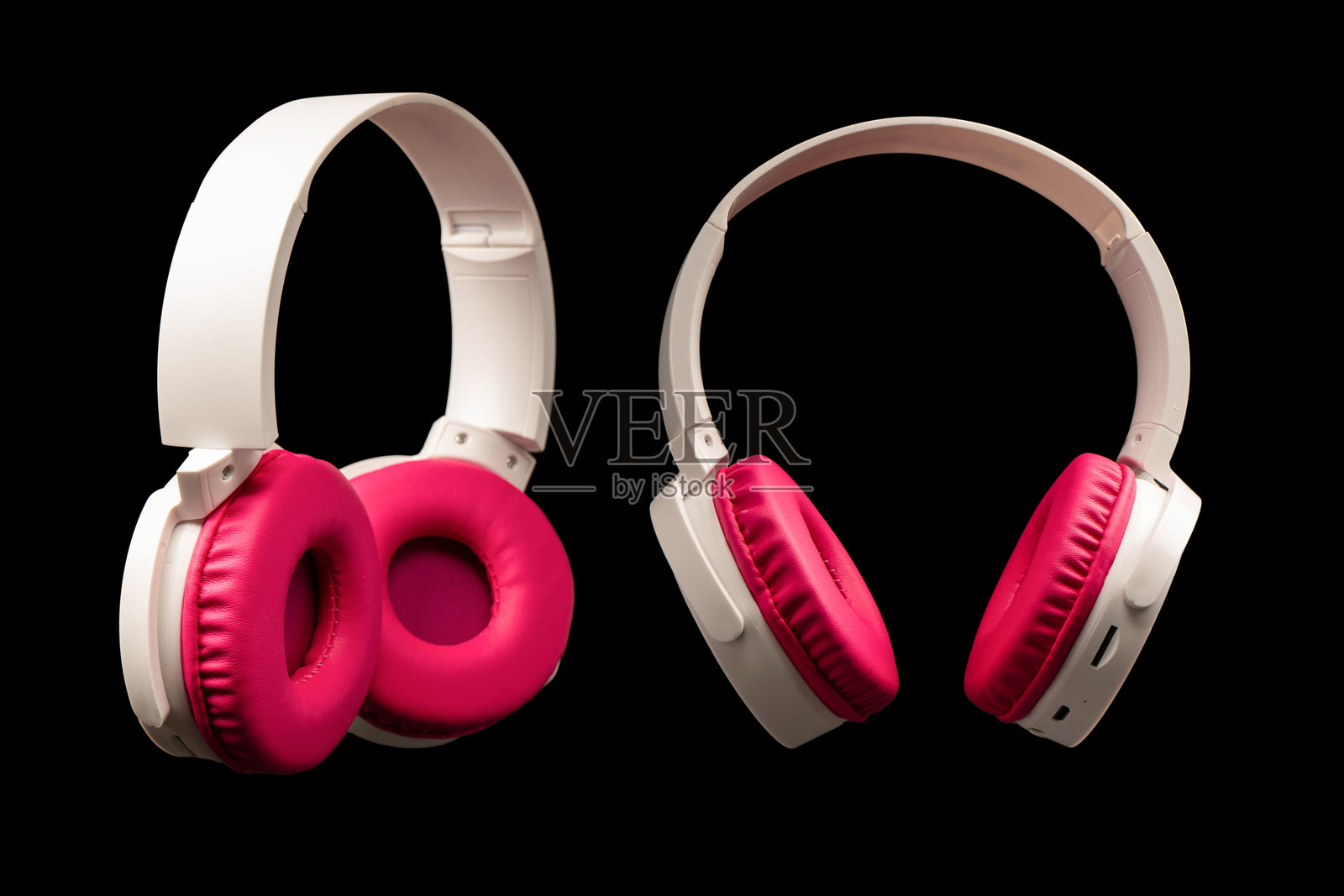 粉色和白色耳机在黑色背景上孤立展示。照片摄影图片