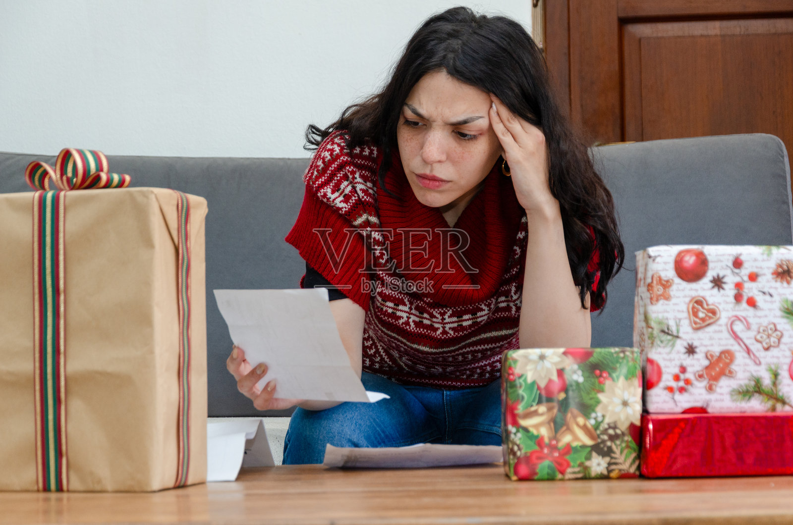 年轻女性在查看购买礼物后的账单，面露担忧。照片摄影图片