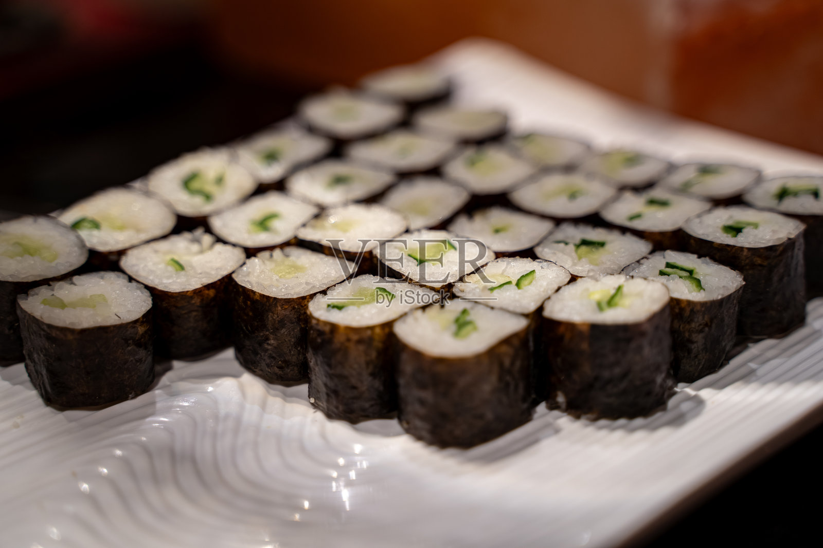 白盘上的黄瓜馅蔬菜寿司卷特写。照片摄影图片